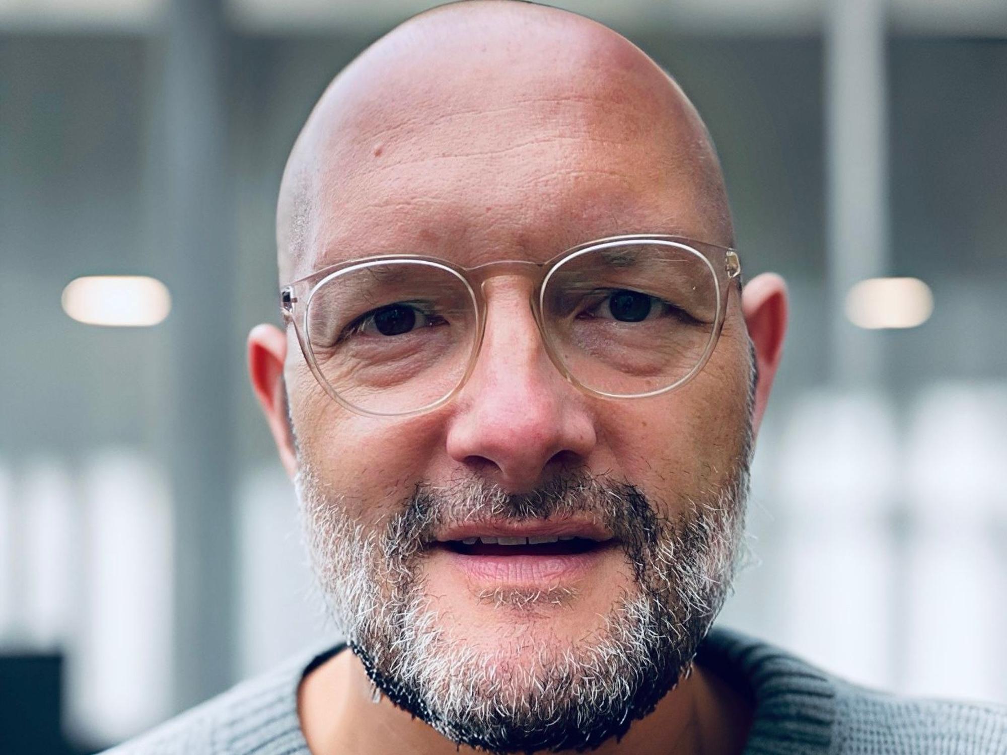 Ein Mann mit Brille und Glatze schaut in die Kamera. Es ist der Journalist Jo Failer