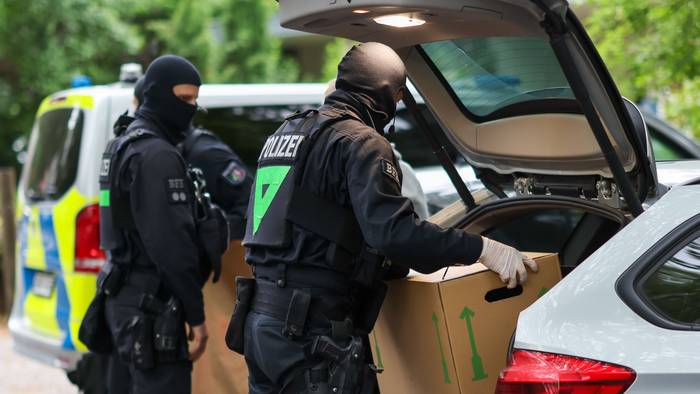 Vermummte Polizisten verlassen bei einem Einsatz ein Gebäude mit sichergestellten Gegenständen. (Symbolfoto)