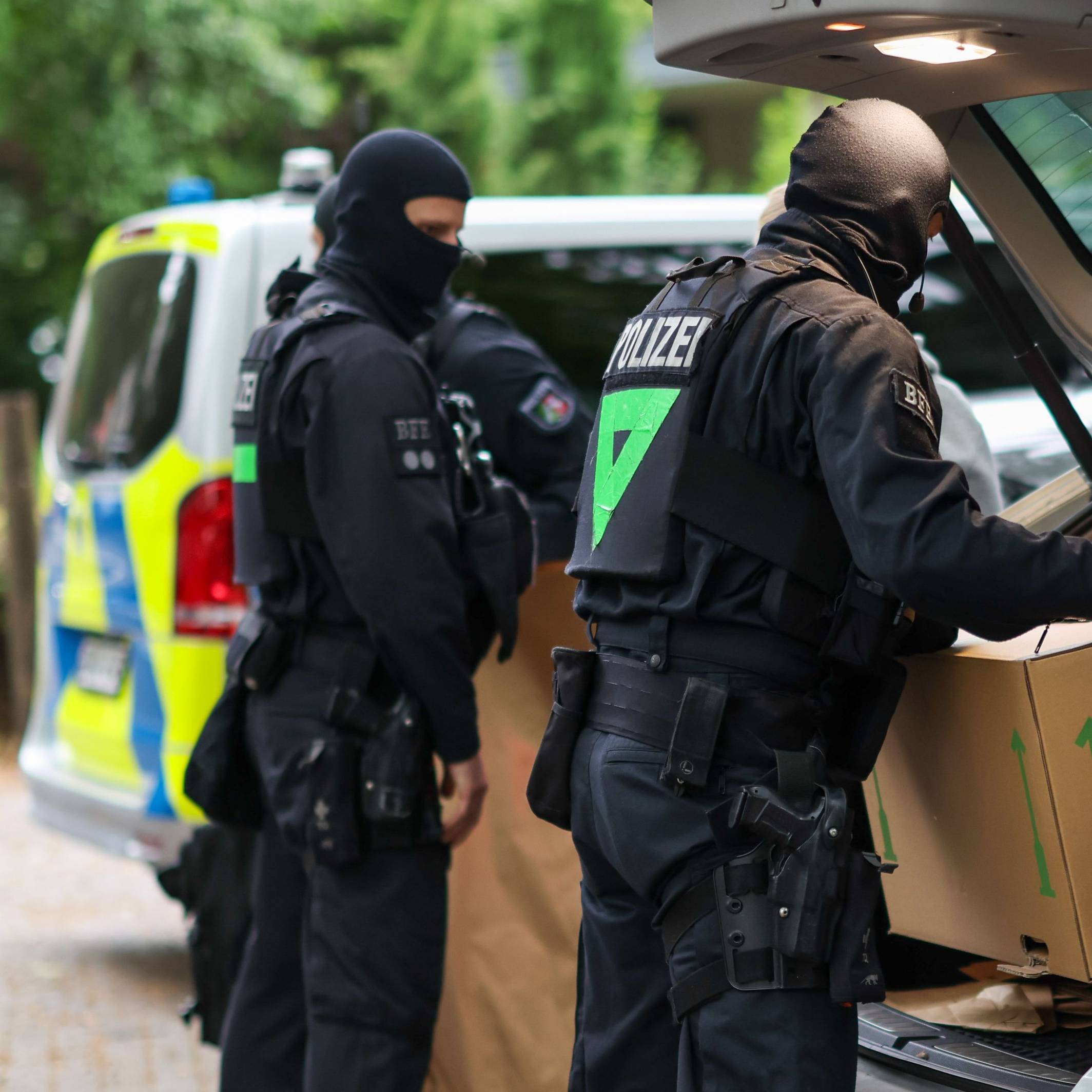 Vermummte Polizisten verlassen bei einem Einsatz ein Gebäude mit sichergestellten Gegenständen. (Symbolfoto)
