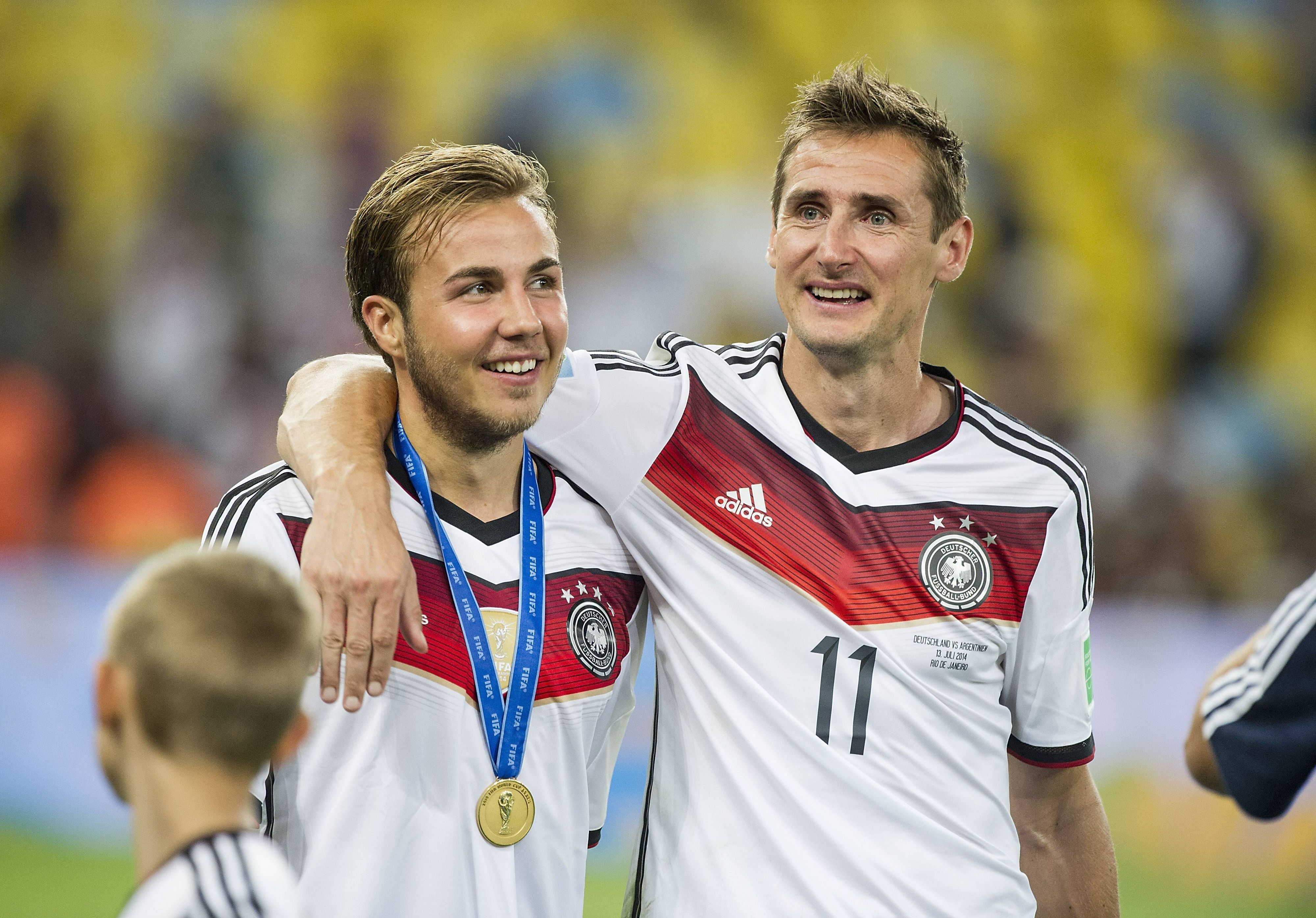 Mario Götze und Miroslav Klose laufen Arm in Arm über den Platz.