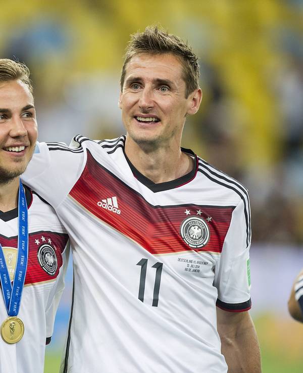 Mario Götze und Miroslav Klose laufen Arm in Arm über den Platz.