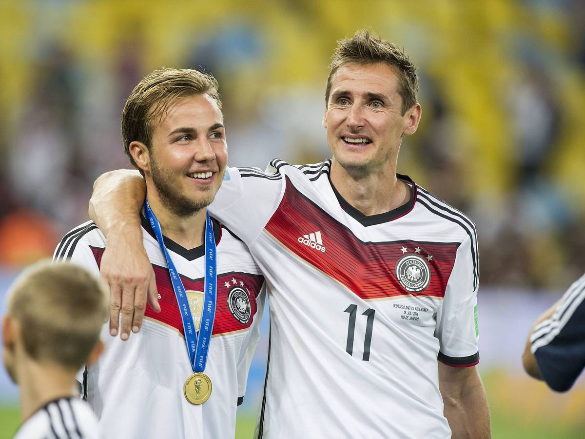 Mario Götze und Miroslav Klose laufen Arm in Arm über den Platz.