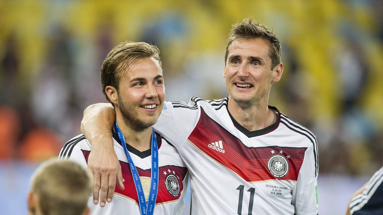 Mario Götze und Miroslav Klose laufen Arm in Arm über den Platz.