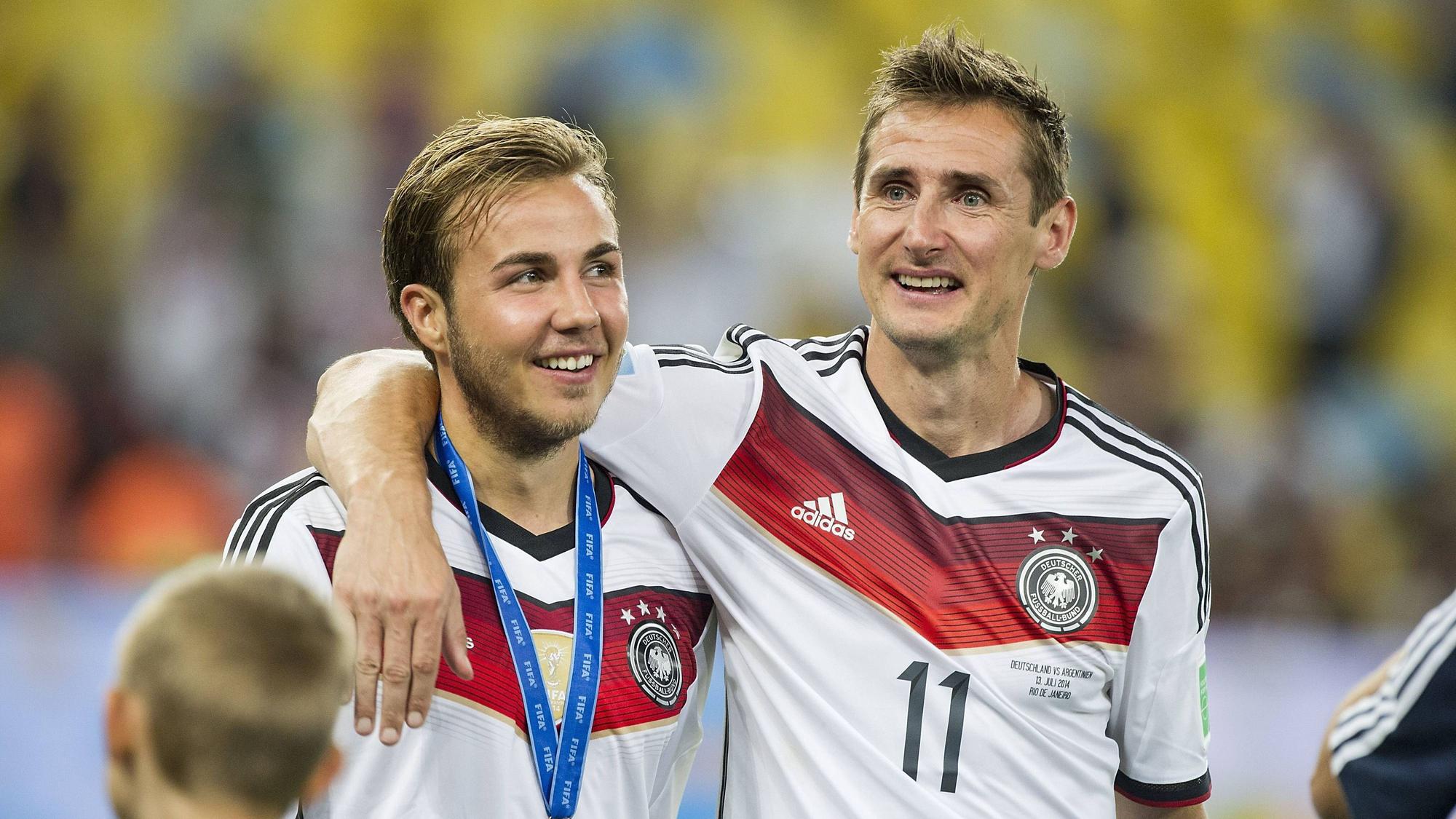 Mario Götze und Miroslav Klose laufen Arm in Arm über den Platz.