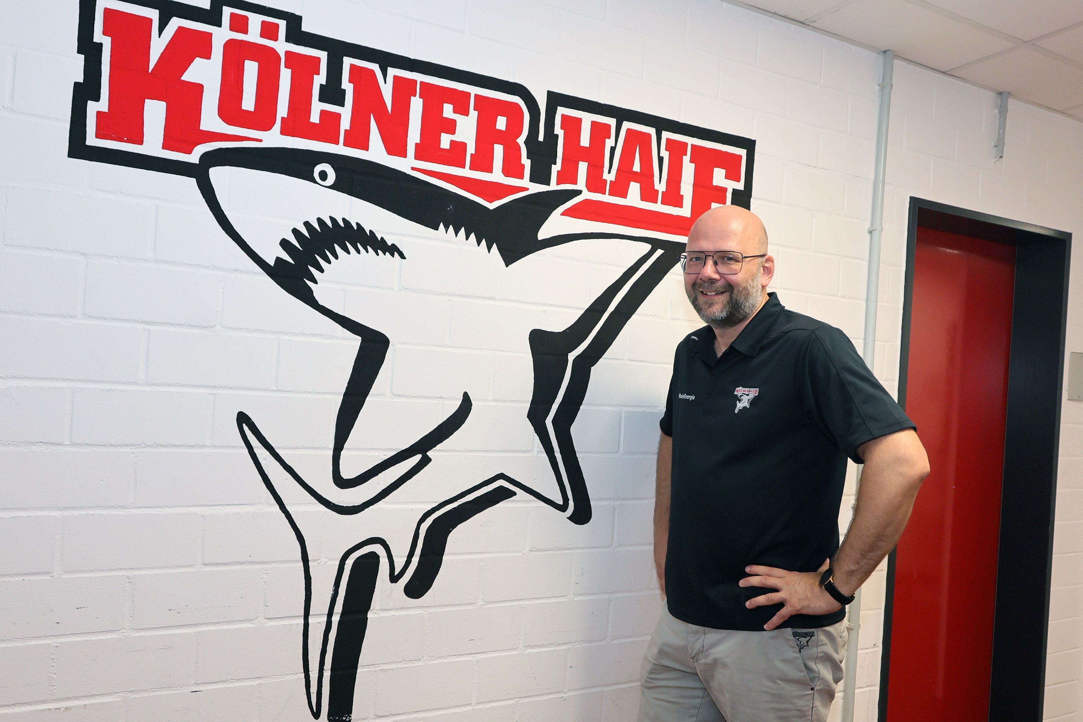 Philipp Walter, Geschäftsführer der Kölner Haie vor dem Klublogo.