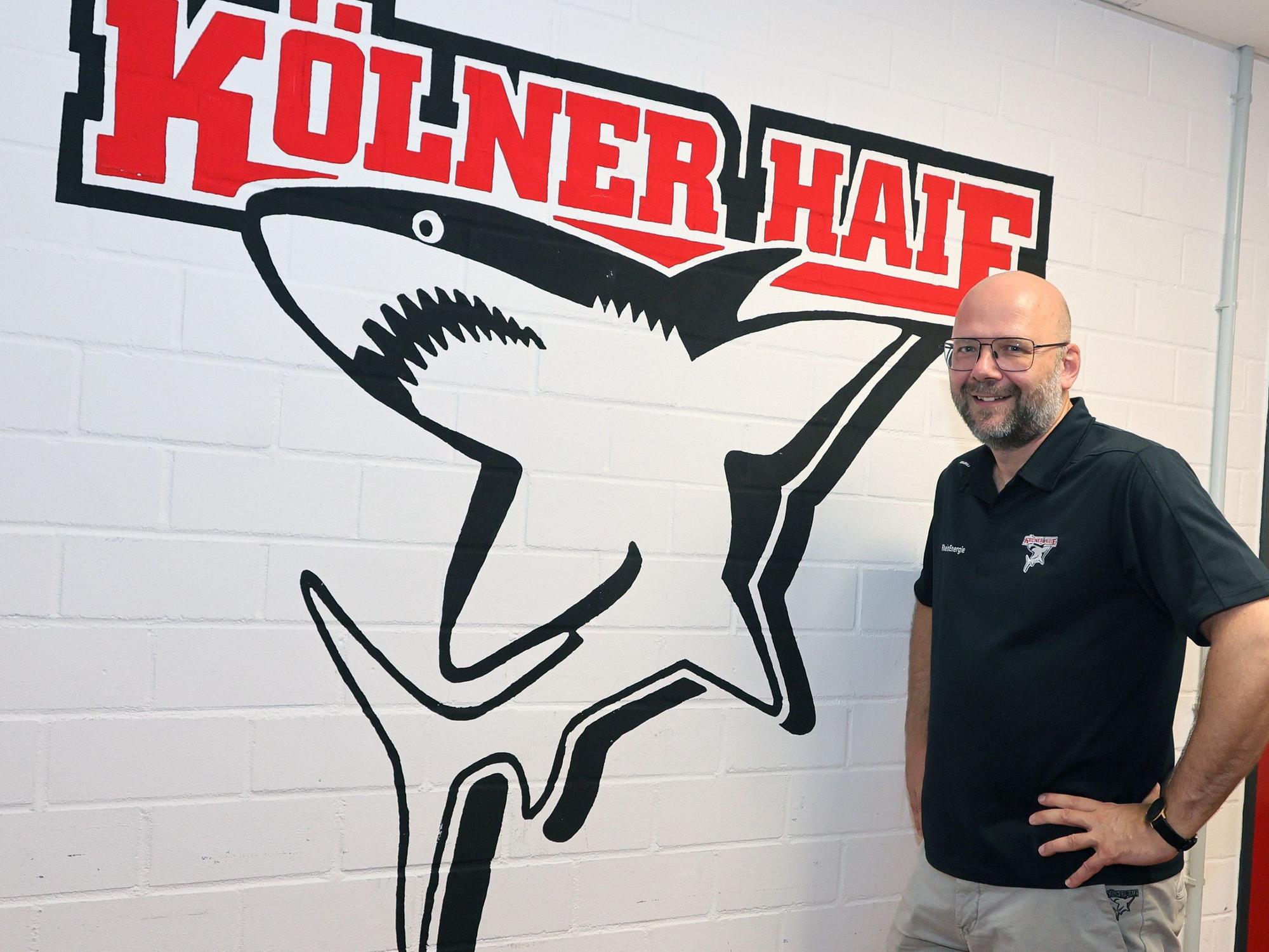 Philipp Walter, Geschäftsführer der Kölner Haie vor dem Klublogo.
