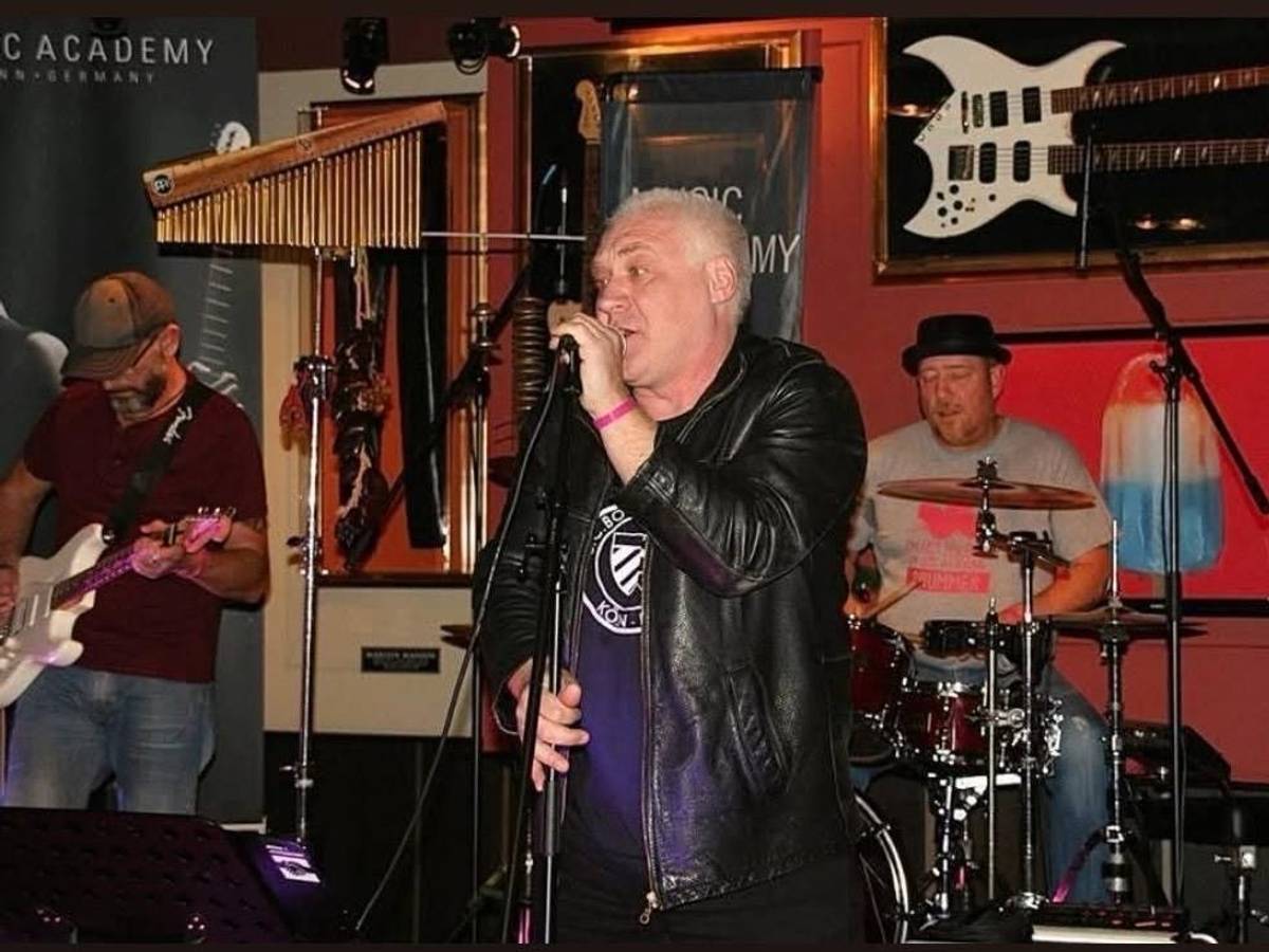 Kalle Gerigk steht auf einer Bühne und singt in ein Mikrofon.