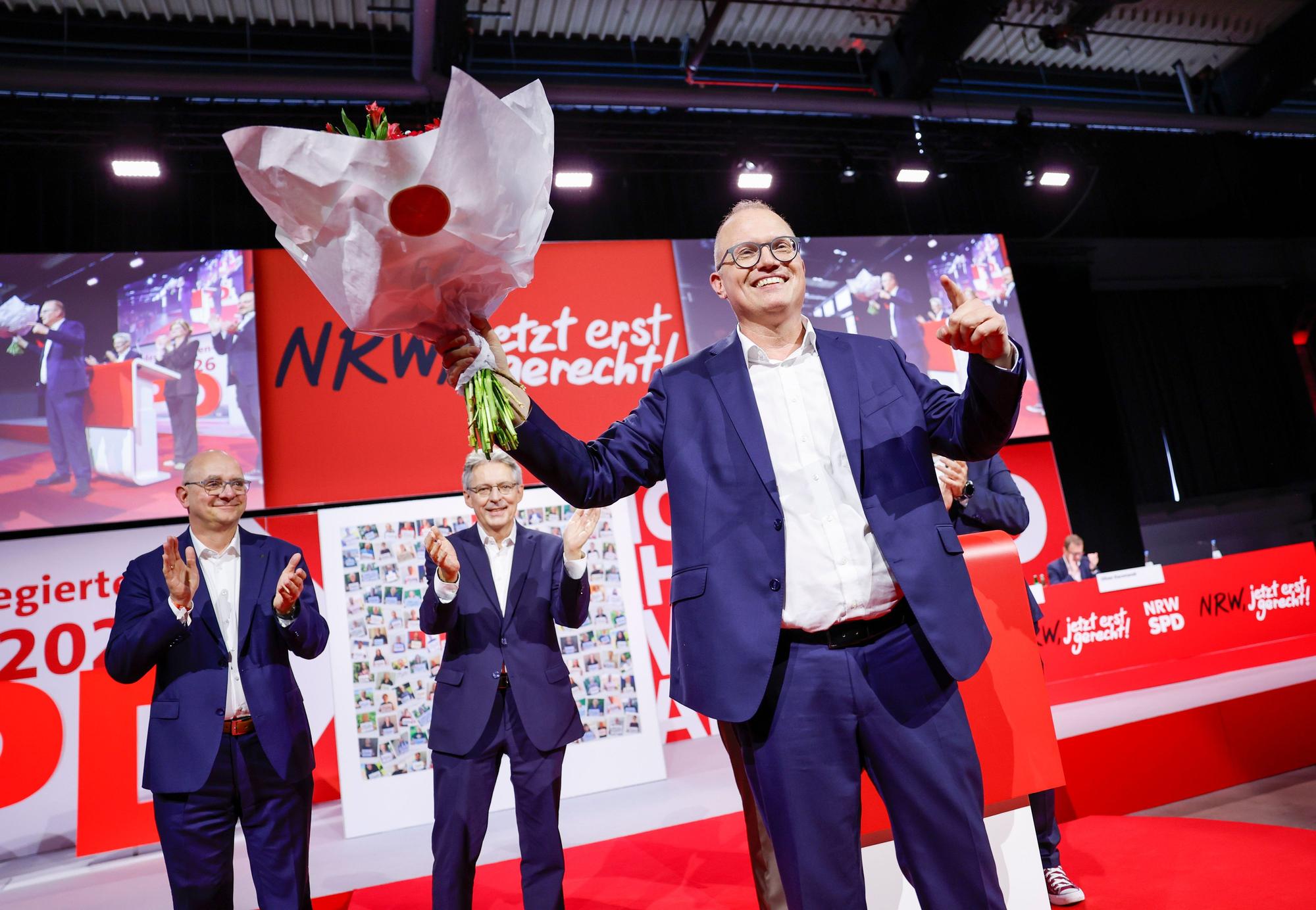 Jochen Ott (SPD) (r), Vorsitzender der SPD-Landtagsfraktion, steht nach der Wahl zum Spitzenkandidaten für die Landtagswahl 2027 vor André Stinka (SPD), Mitglied des Landtags, und Achim Post, Vorsitzender der SPD Nordrhein-Westfalen, bei der Landesdelegiertenkonferenz auf der Bühne.