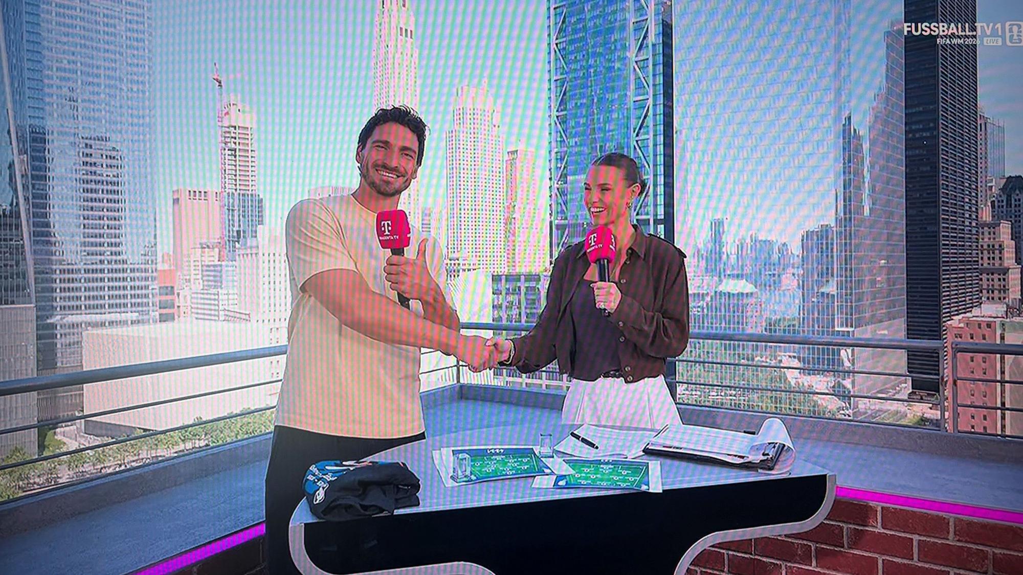 Mats Hummels und Laura Wontorra schütteln sich die Hand.