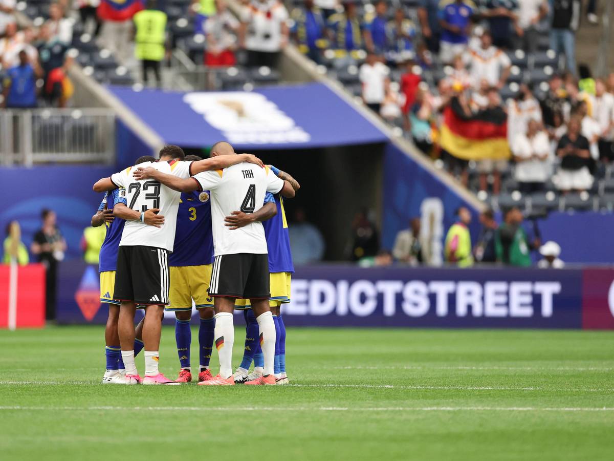 Felix Nmecha und Jonathan Tah stehen Arm in Arm mit Curacao-Spielern in einem Kreis zusammen.
