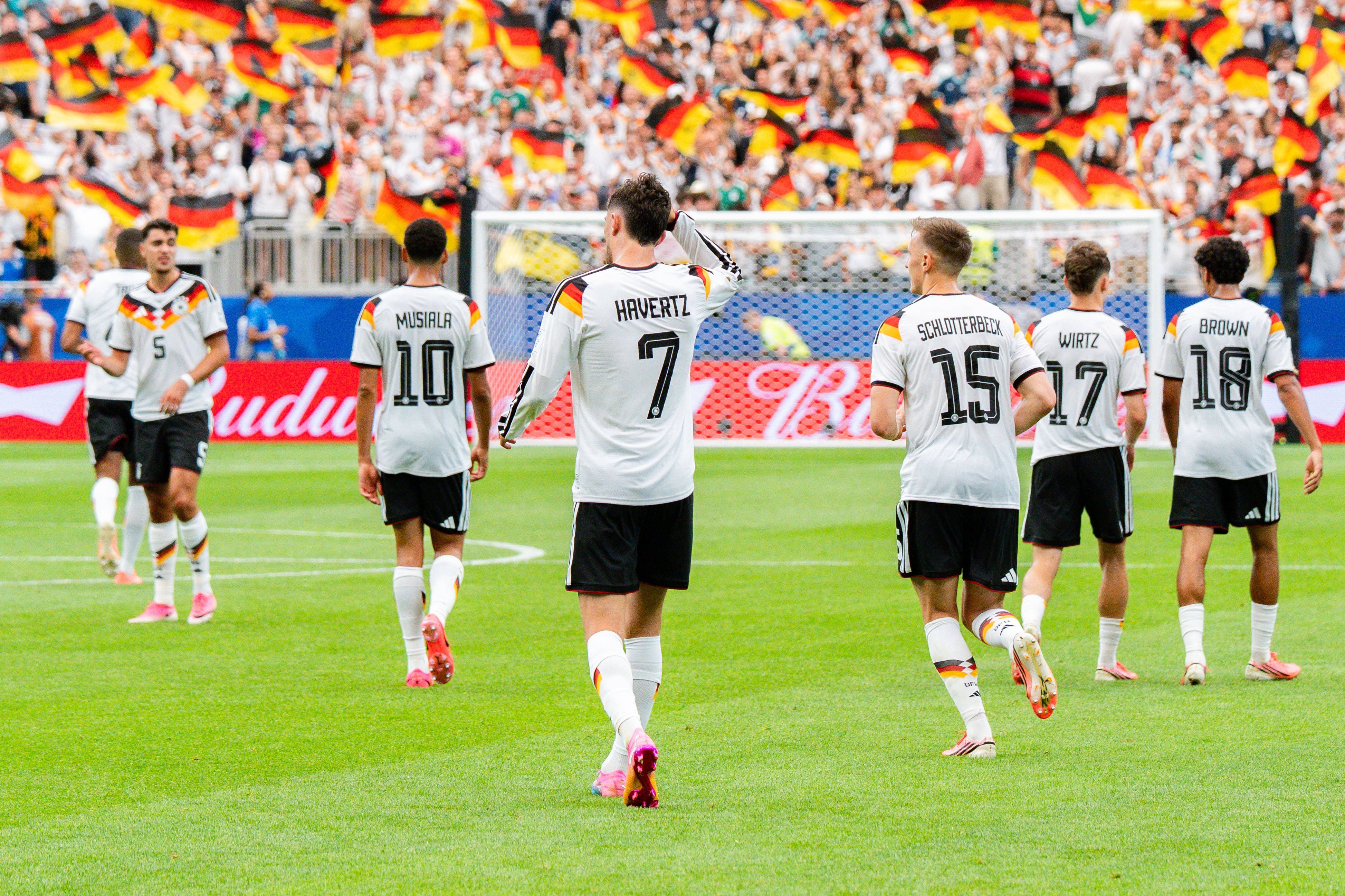 Deutsche Spieler jubeln, im Hintergrund schwenken Fans deutsche Fahnen.
