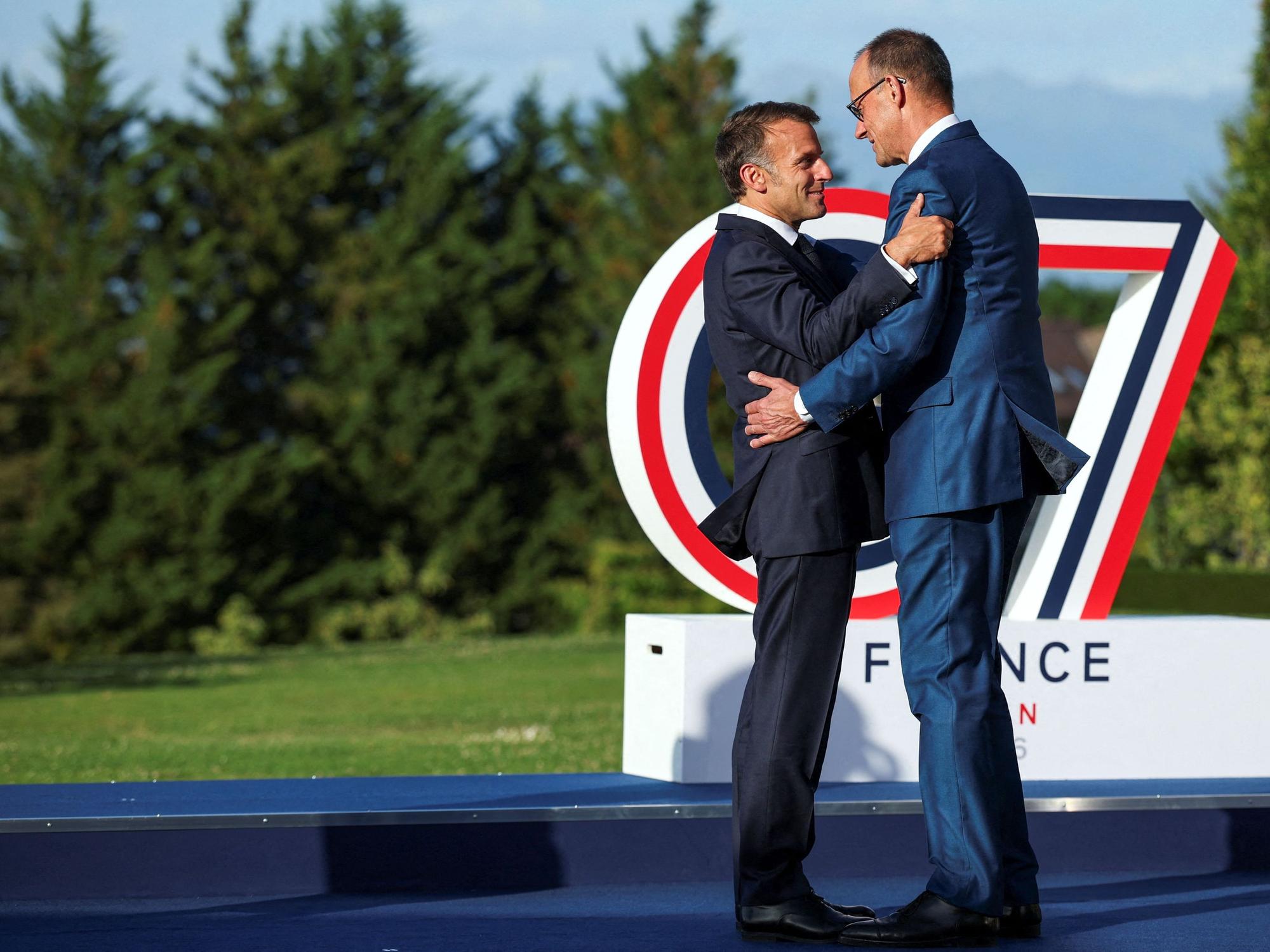 Frankreichs Präsident Emmanuel Macron (l.) begrüßt Bundeskanzler Friedrich Merz beim G7-Gipfel.