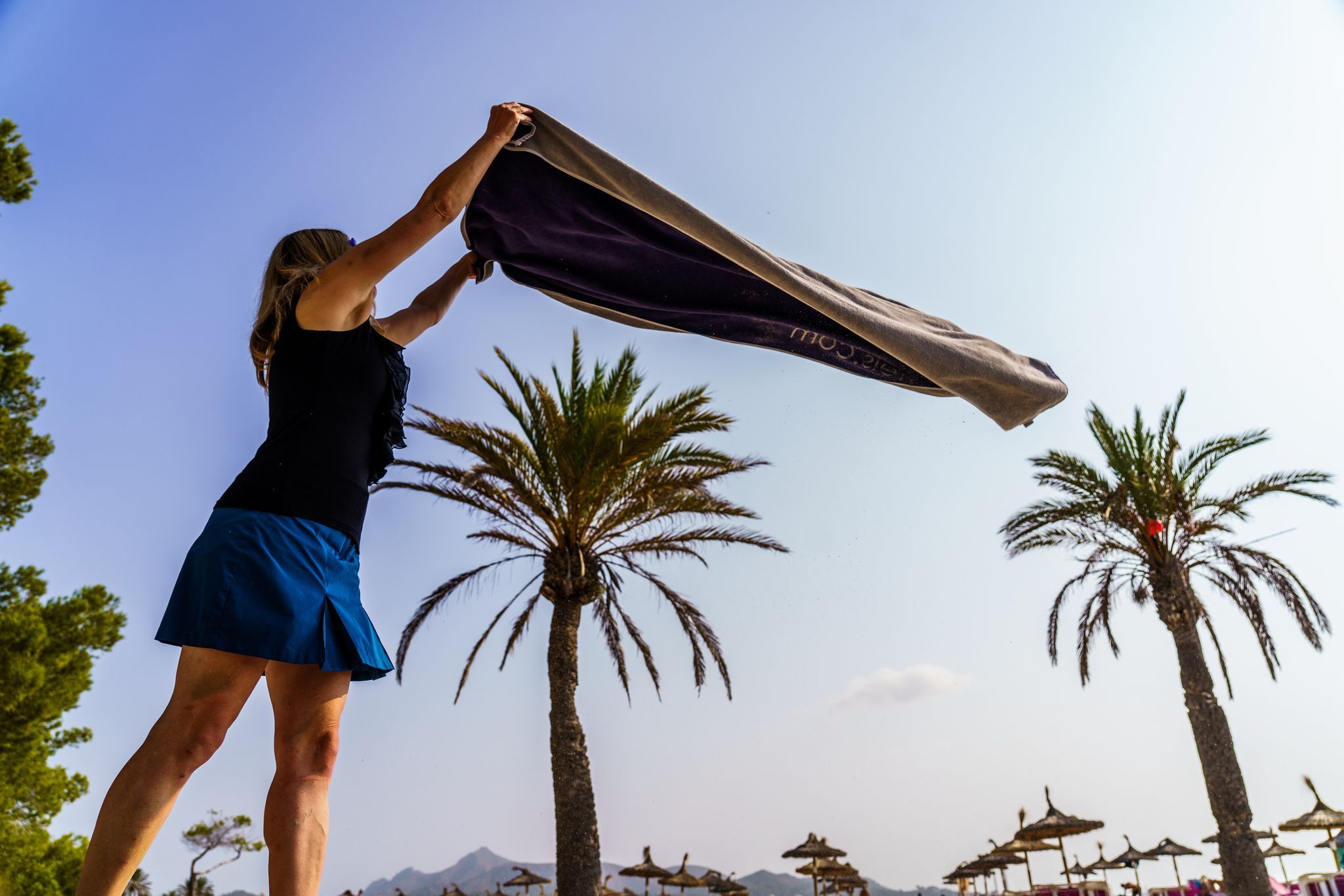 Eine Frau breitet am Strand ihr Handtuch aus