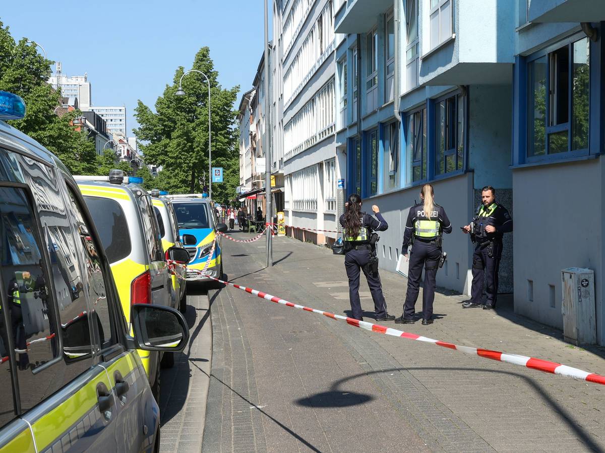 Drei Polizeikräfte stehen vor einem Haus, der Bereich davor ist mit Flatterband abgesperrt.