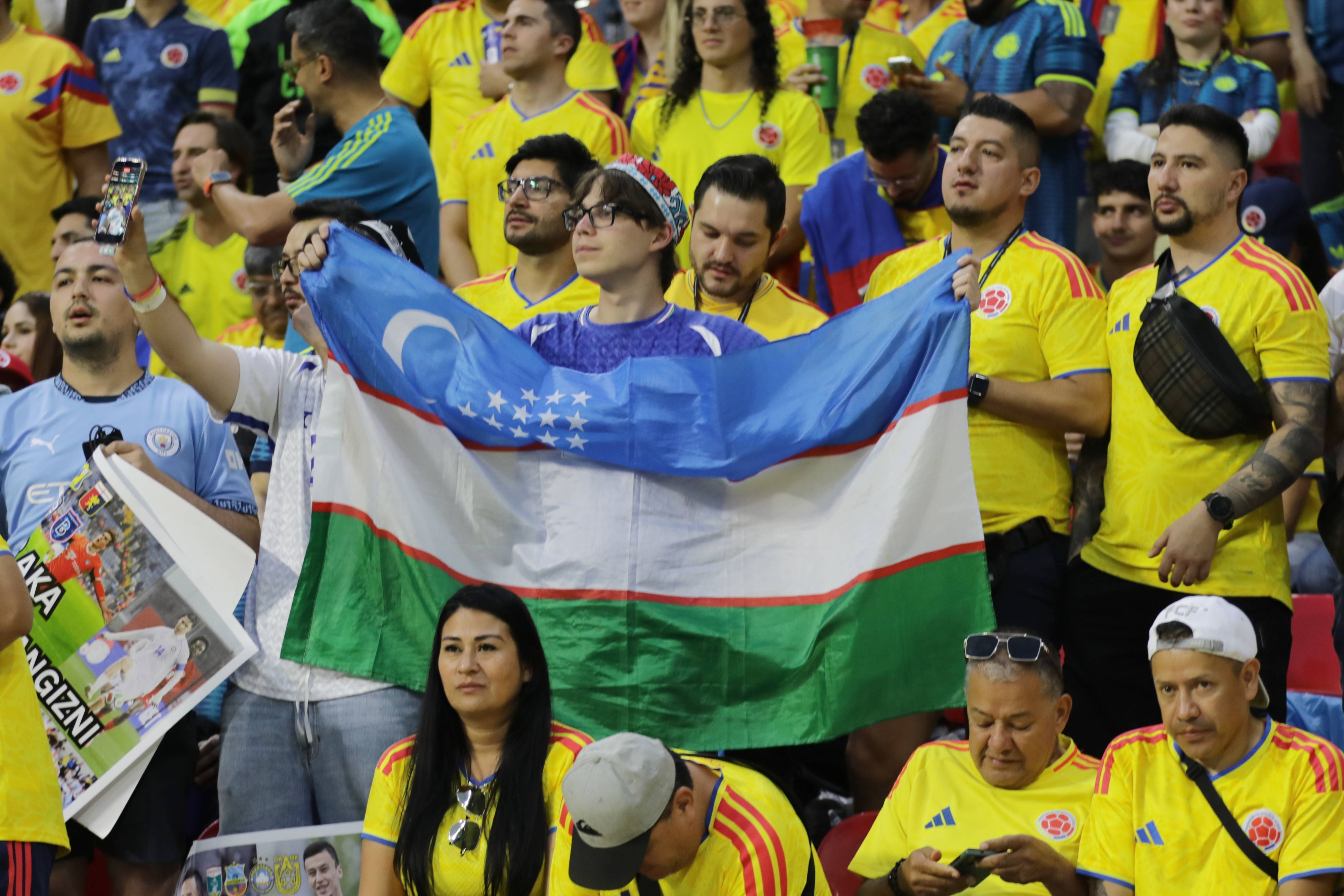 Ein Fan mit Usbekistan-Flagge steht inmitten von kolumbianischen Fans.