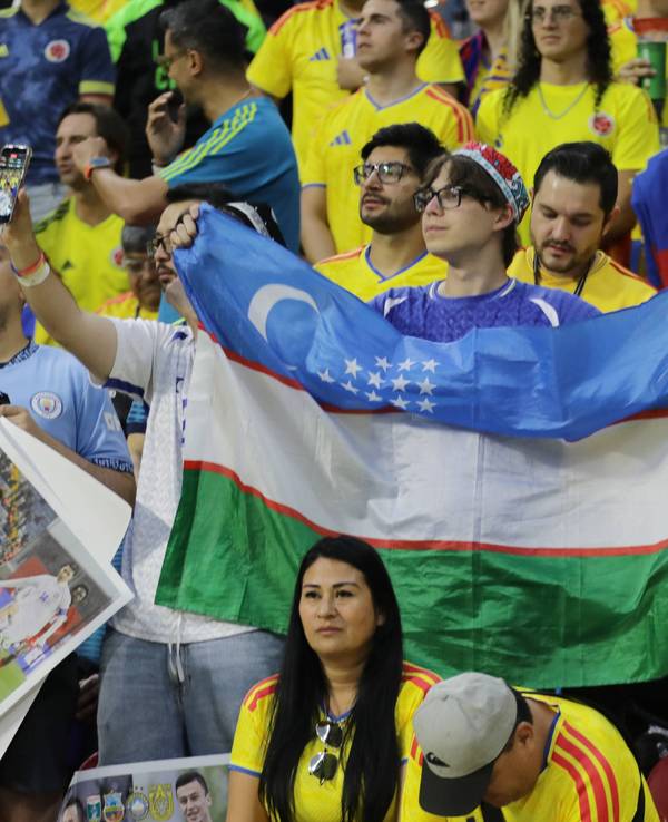 Ein Fan mit Usbekistan-Flagge steht inmitten von kolumbianischen Fans.
