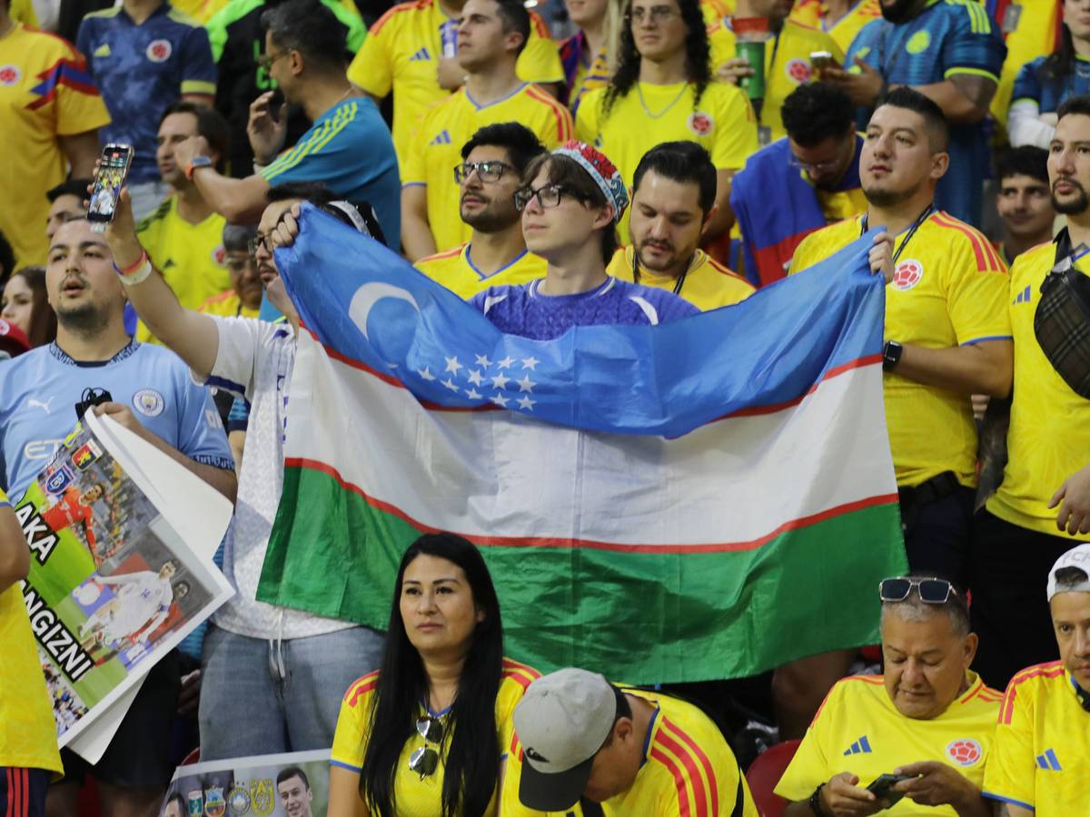 Ein Fan mit Usbekistan-Flagge steht inmitten von kolumbianischen Fans.