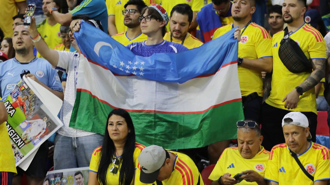 Ein Fan mit Usbekistan-Flagge steht inmitten von kolumbianischen Fans.