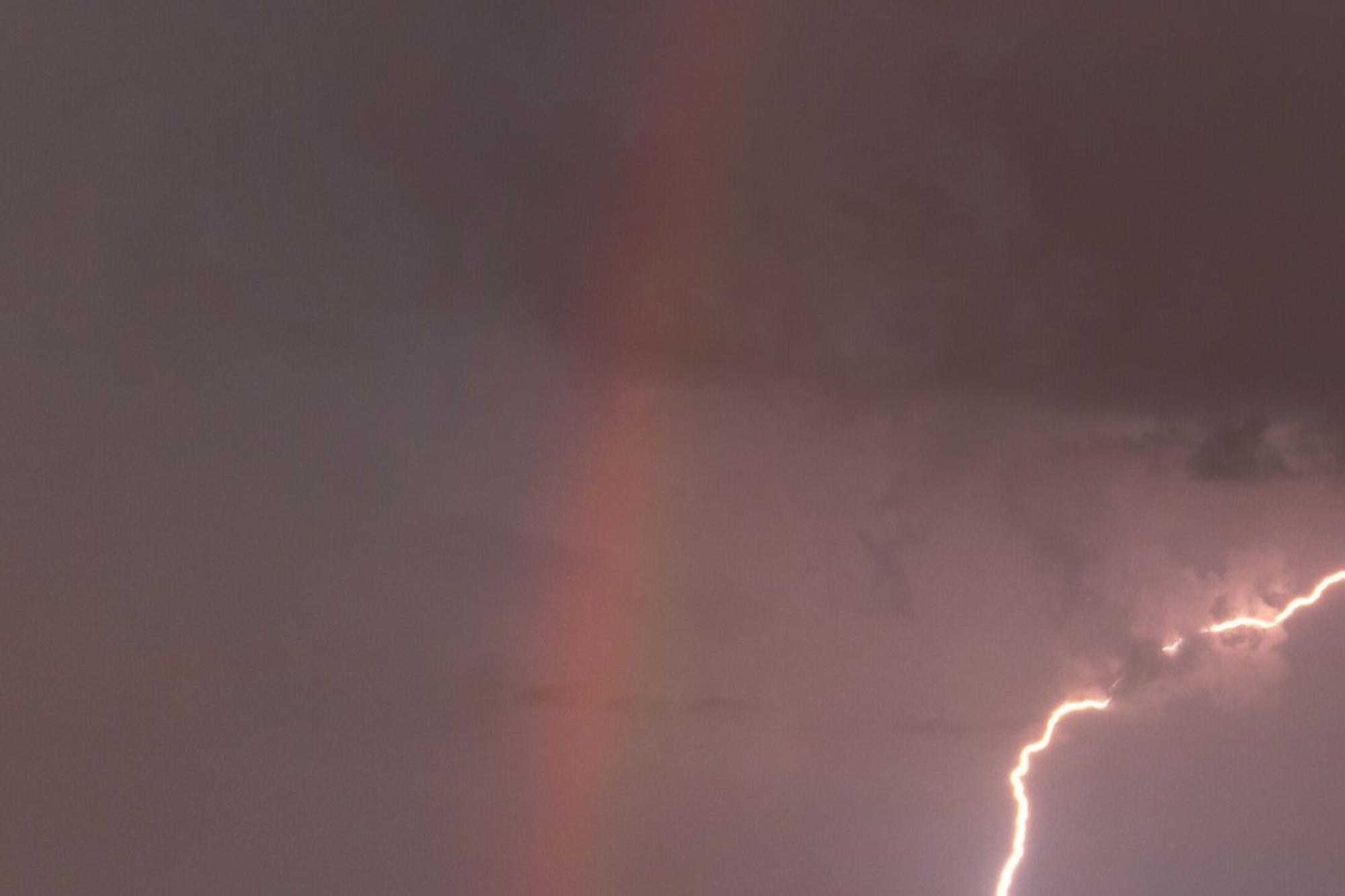 Blitz entlädt sich neben einem Regenbogen am Templiner See