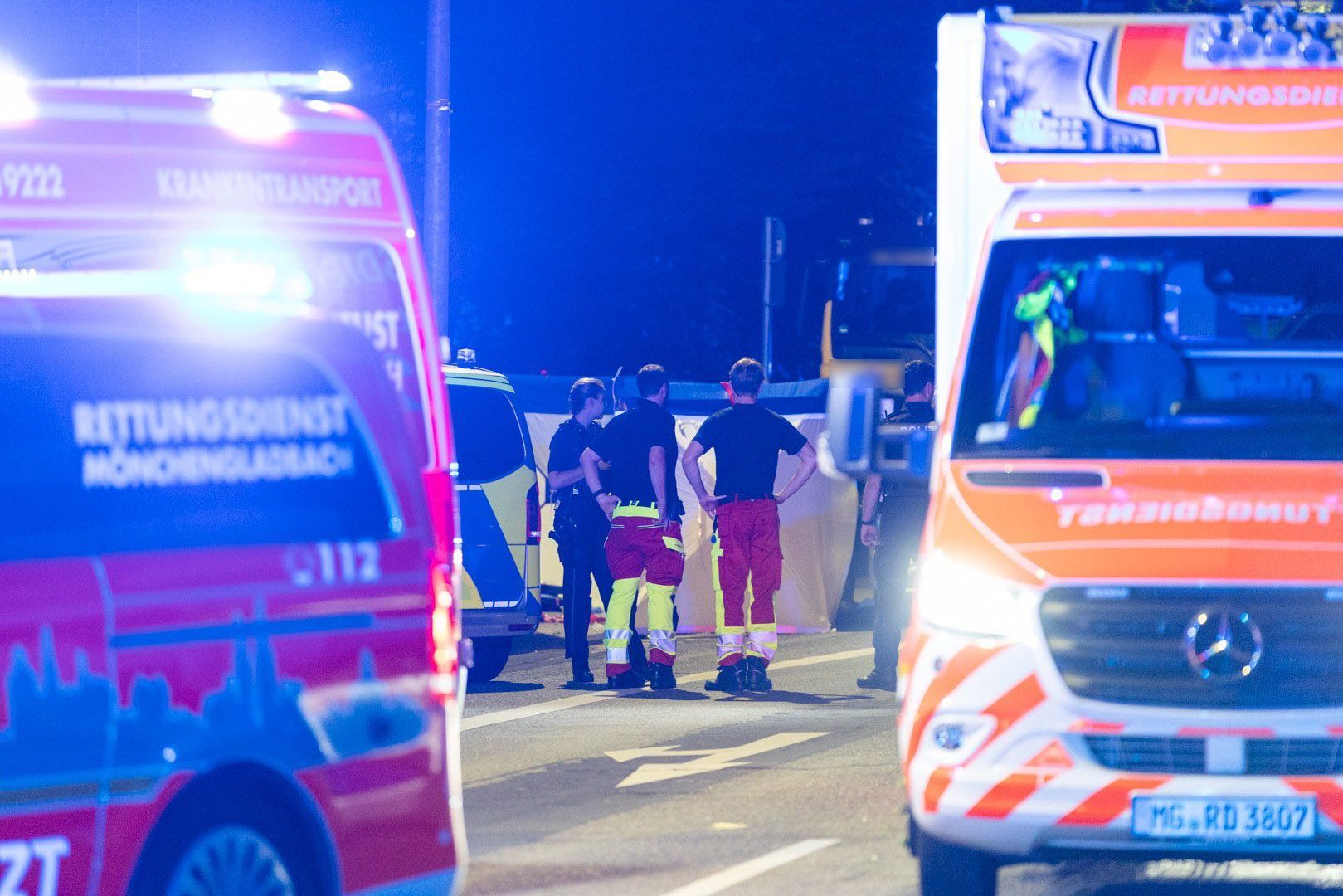 Einsatzkräfte stehen zusammen auf der Straße. Bei einem Polizeieinsatz an einer Tankstelle in Mönchengladbach hat die Polizei auf eine 18-Jährige geschossen, die den Angaben zufolge ein Messer mitführte.