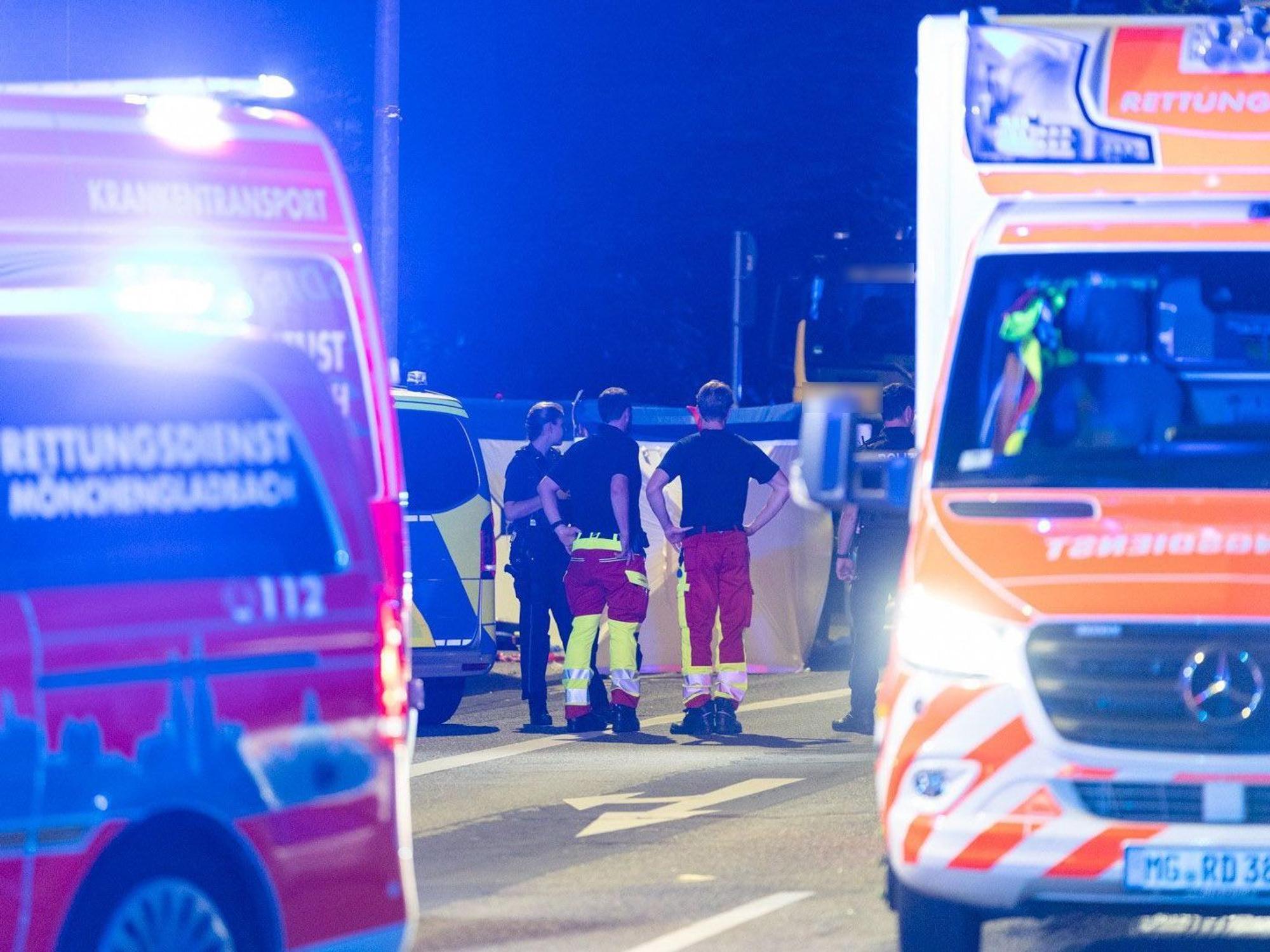 Einsatzkräfte stehen zusammen auf der Straße. Bei einem Polizeieinsatz an einer Tankstelle in Mönchengladbach hat die Polizei auf eine 18-Jährige geschossen, die den Angaben zufolge ein Messer mitführte.