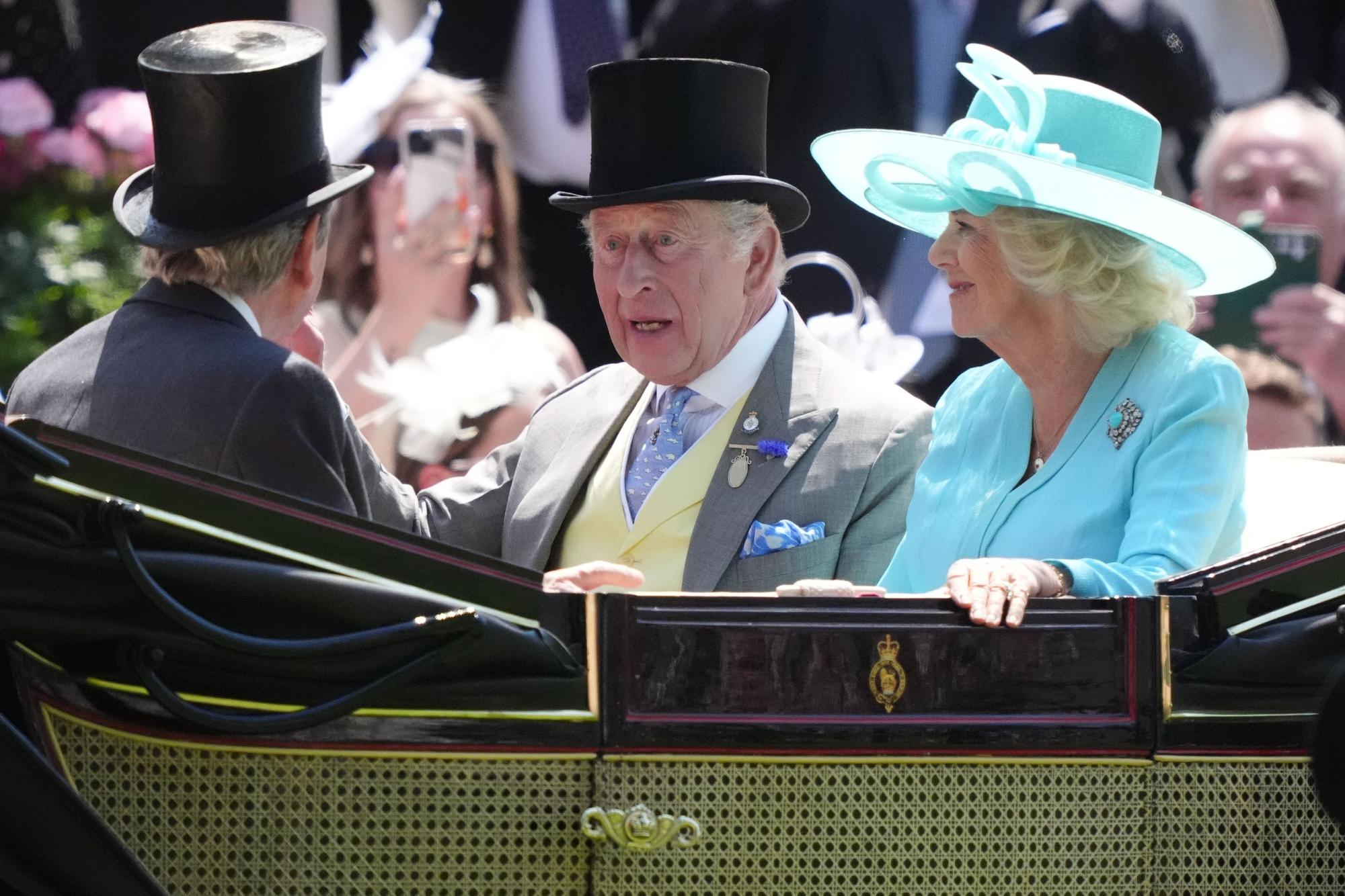 König Charles III. (hinten,r) und Königin Camilla fahren mit einer Kutsche am vierten Tag des Ascot Pferderennens an der Rennstrecke vor.