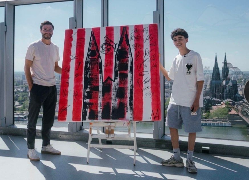 Der 13-jährige Künstler Mikail Akar und Jonas Hector mit dem FC-Kunstwerk in Köln.