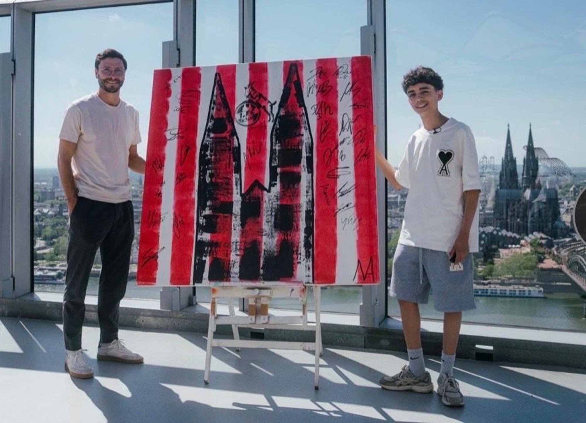 Der 13-jährige Künstler Mikail Akar und Jonas Hector mit dem FC-Kunstwerk in Köln.