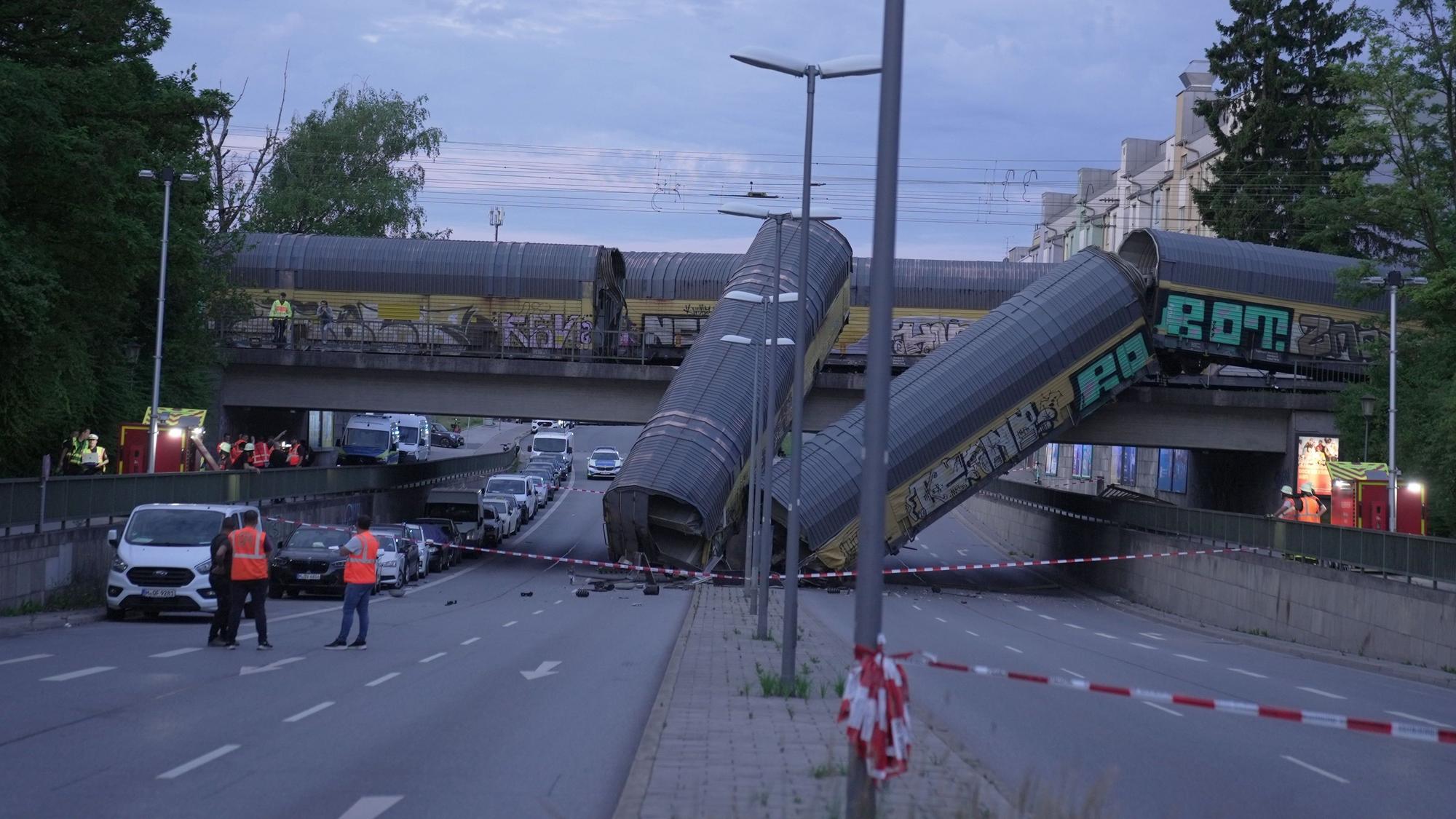 Zwei Waggons eines Güterzugs liegen auf einer Straße, nachdem sie von einer Brücke gestürzt sind.
