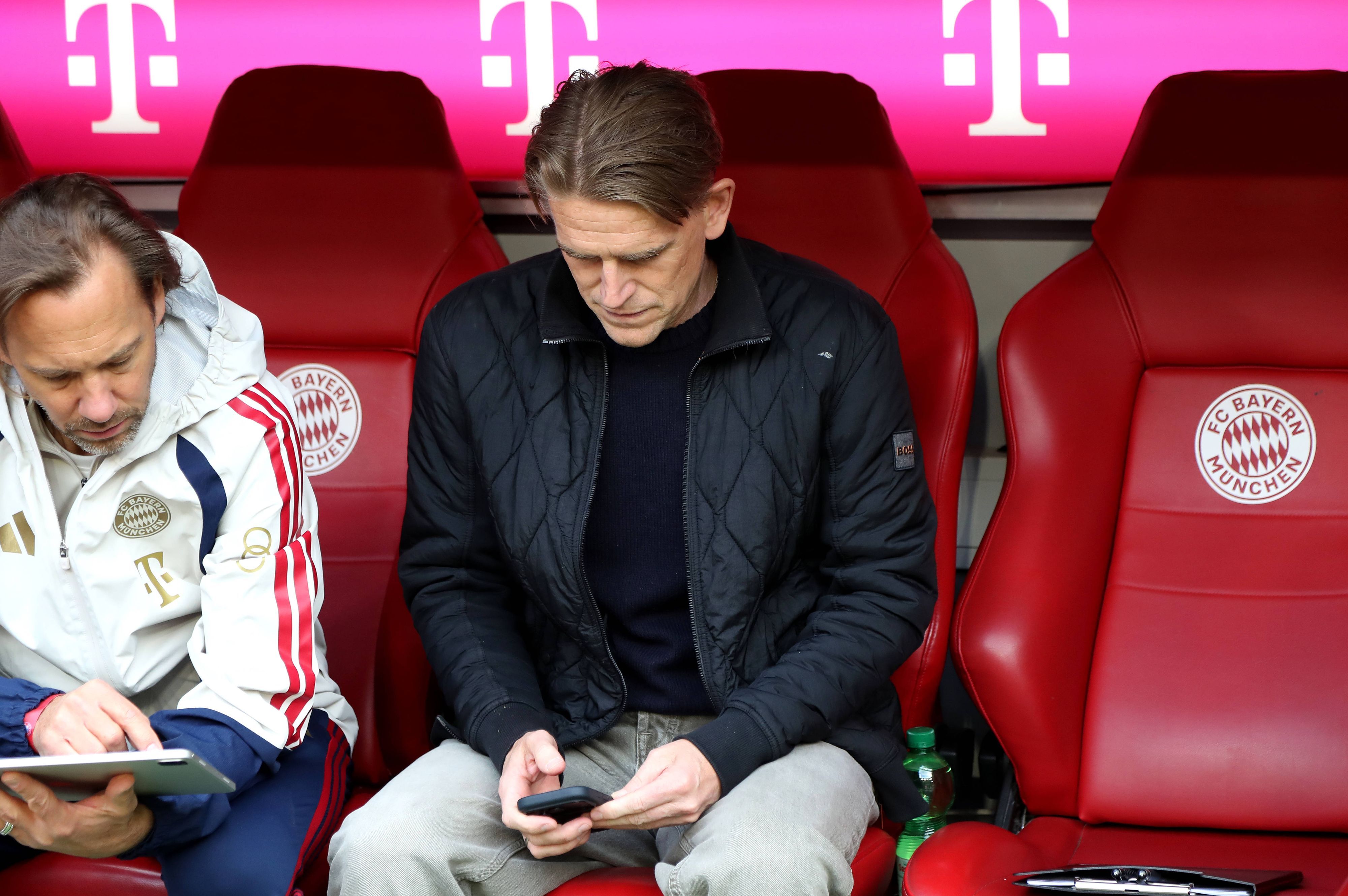 Christoph Freund sitzt auf der Ersatzbank und schaut auf sein Handy.