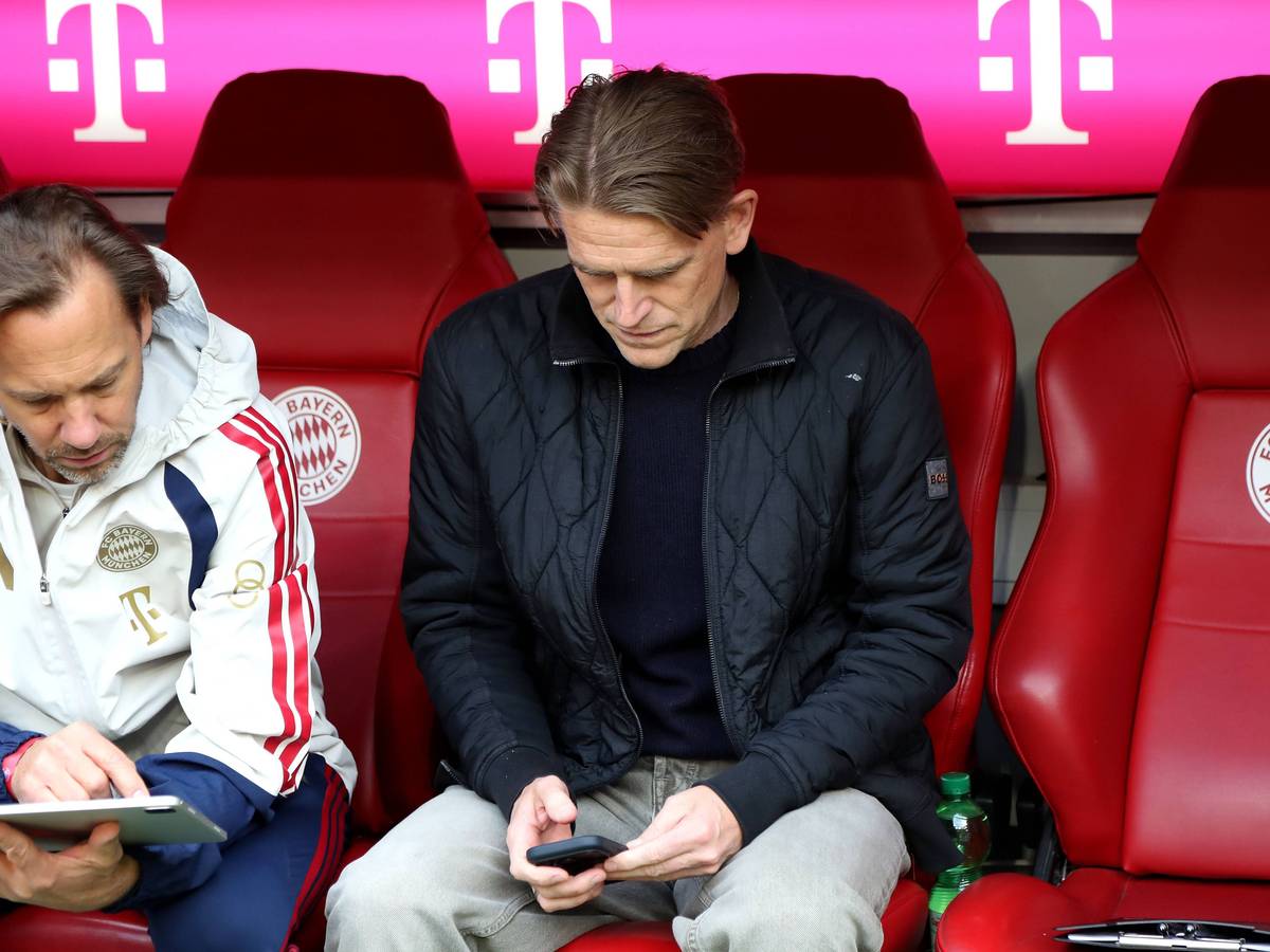 Christoph Freund sitzt auf der Ersatzbank und schaut auf sein Handy.
