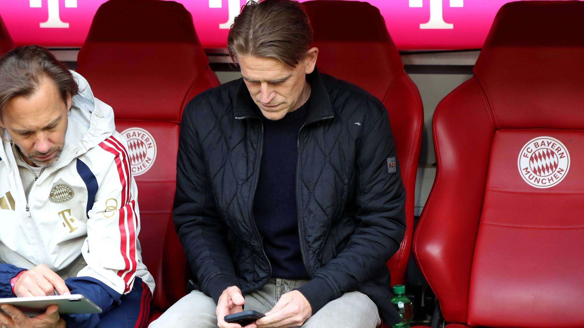 Christoph Freund sitzt auf der Ersatzbank und schaut auf sein Handy.