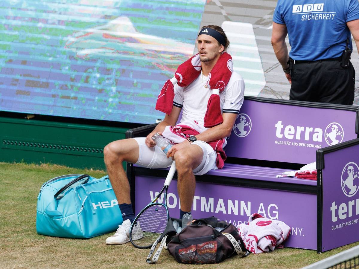 Alexander Zverev sitzt völlig fertig mit einem Kühlpad um den Hals auf der Bank beim Seitenwechsel.