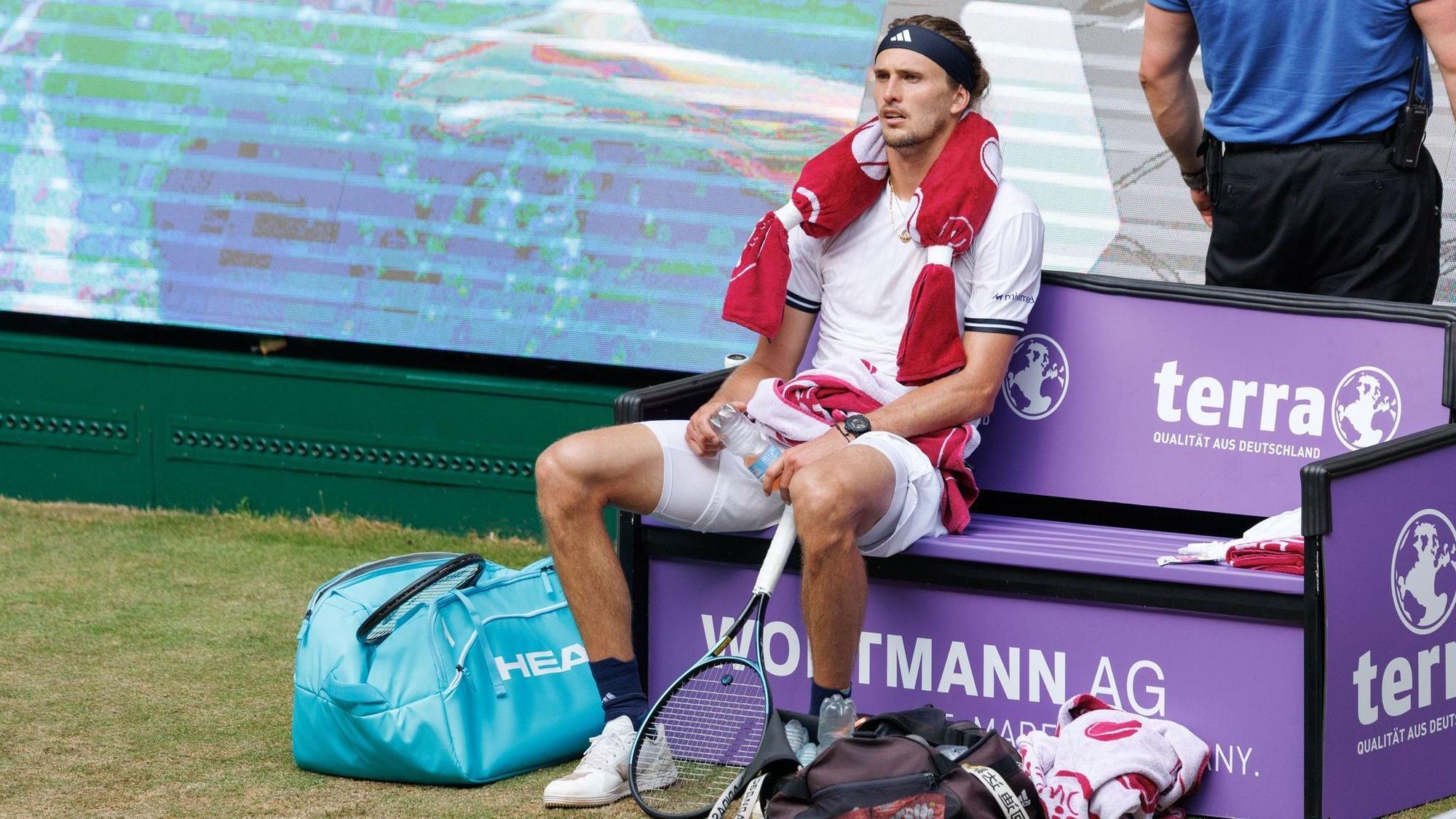Alexander Zverev sitzt völlig fertig mit einem Kühlpad um den Hals auf der Bank beim Seitenwechsel.