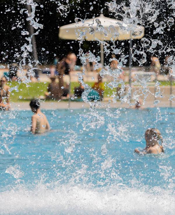 Menschen kühlen sich bei hohen Temperaturen und Sonne im Stadionbad ab.