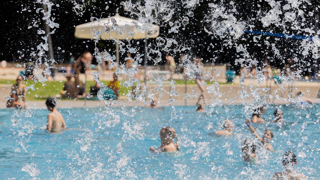 Menschen kühlen sich bei hohen Temperaturen und Sonne im Stadionbad ab.