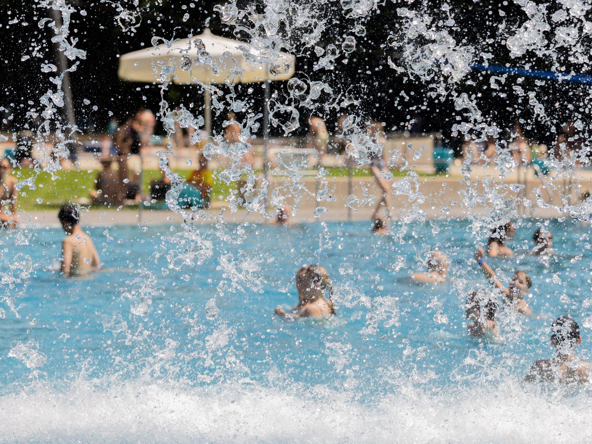 Menschen kühlen sich bei hohen Temperaturen und Sonne im Stadionbad ab.