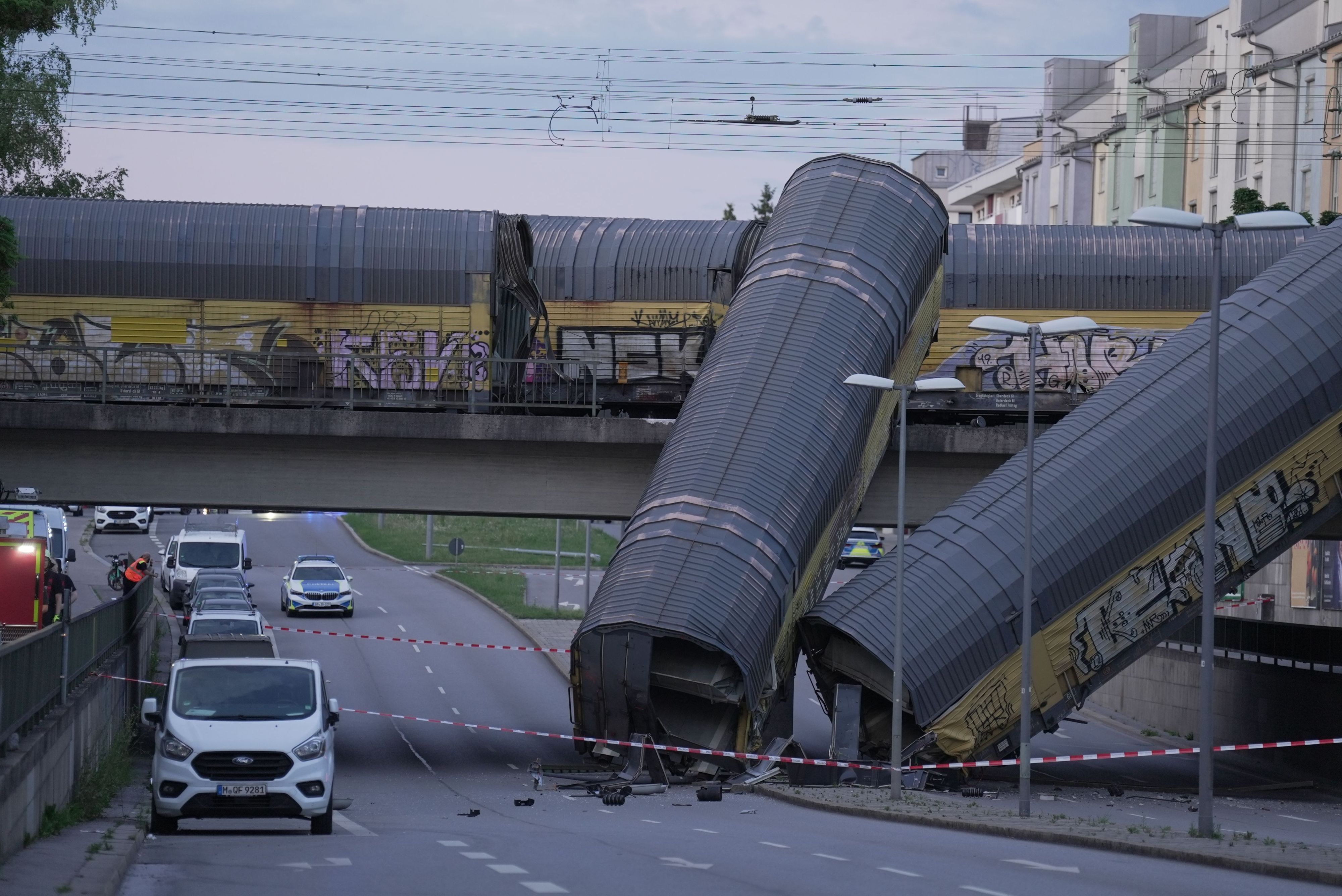 Zwei Waggons eines Güterzugs liegen auf einer Straße, nachdem sie von einer Brücke gestürzt sind.
