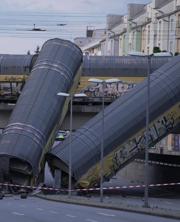 Zwei Waggons eines Güterzugs liegen auf einer Straße, nachdem sie von einer Brücke gestürzt sind.