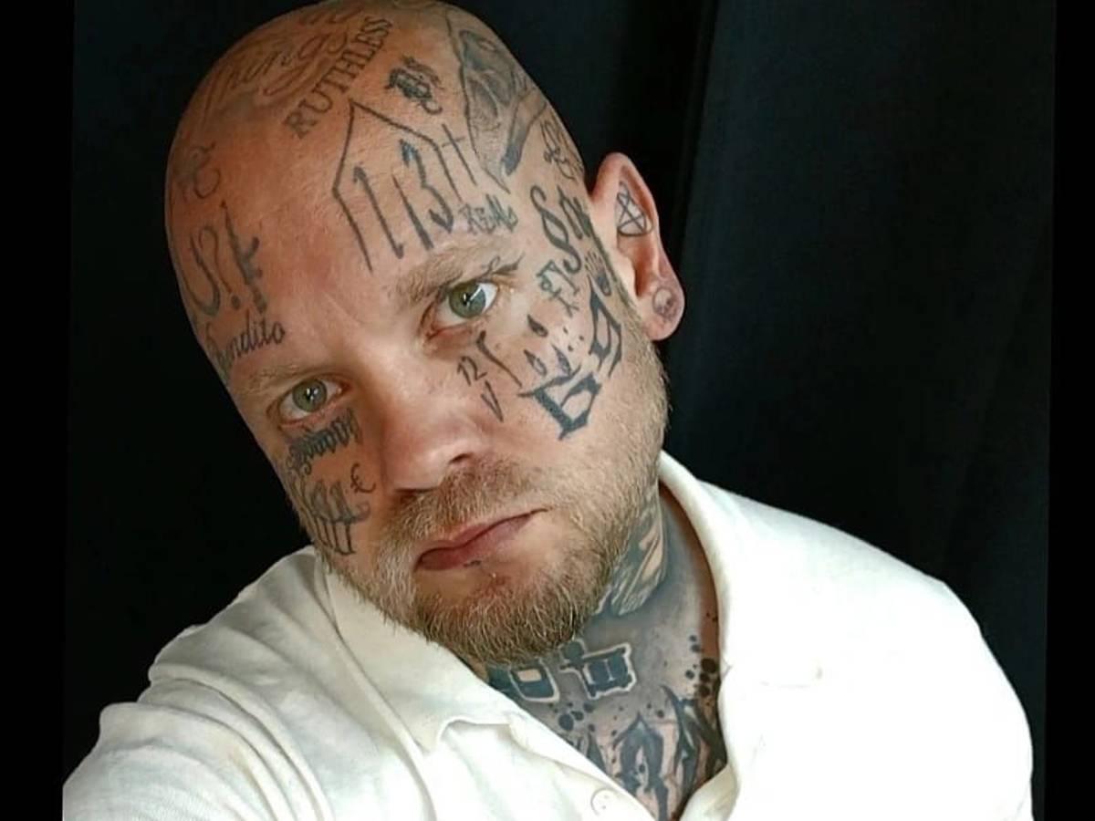 Ein glatzköpfiger Mann, der über und über mit Tätowierungen bedeckt ist