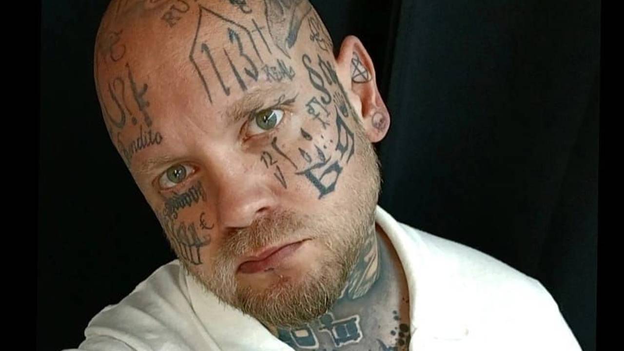 Ein glatzköpfiger Mann, der über und über mit Tätowierungen bedeckt ist