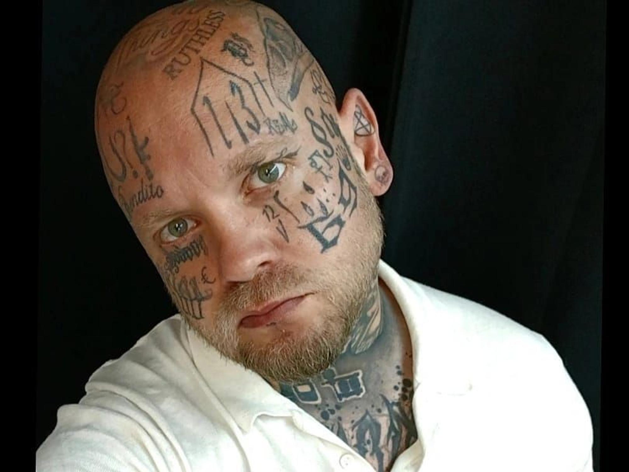 Ein glatzköpfiger Mann, der über und über mit Tätowierungen bedeckt ist