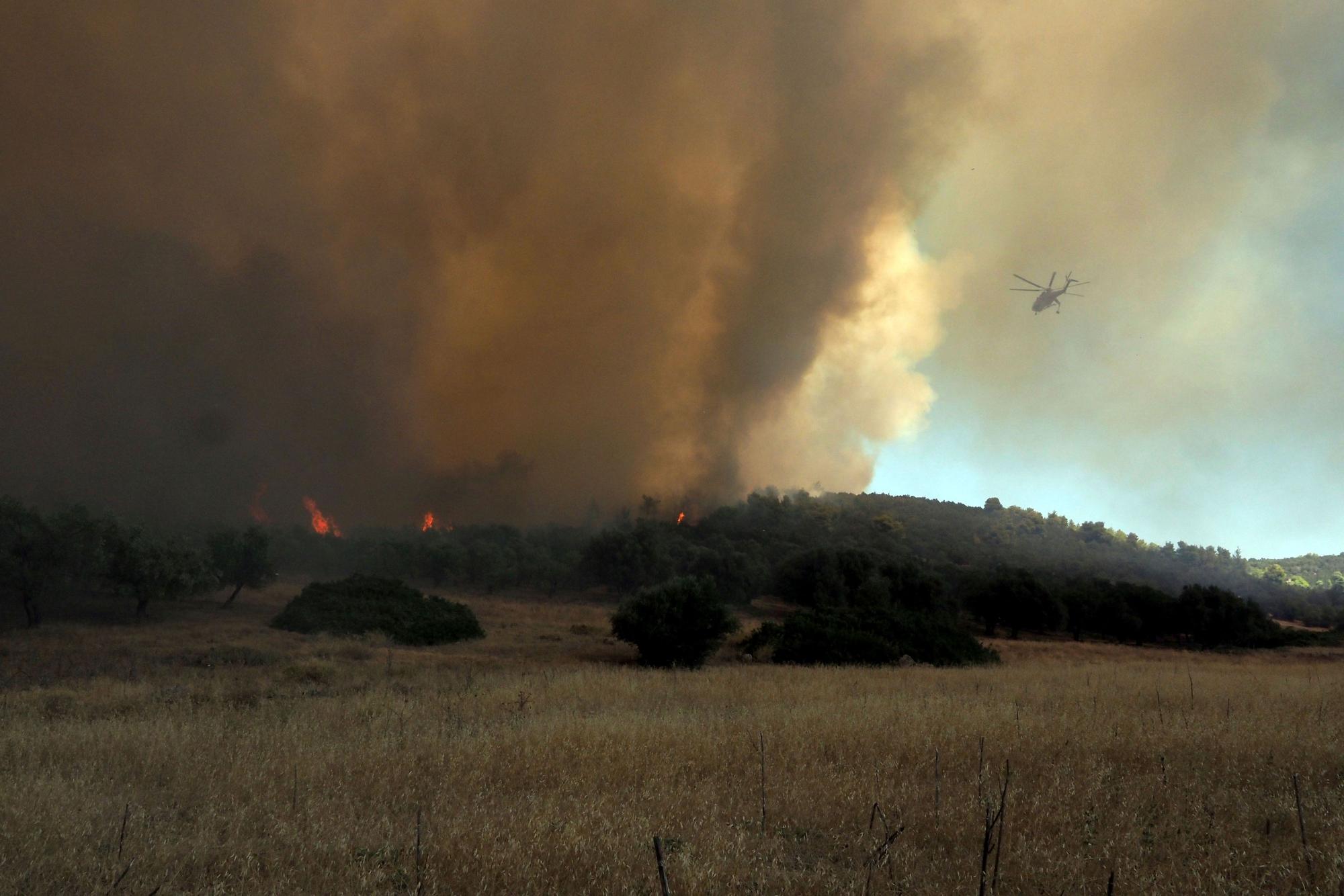 Ein Hubschrauber fliegt am Sonntag (21. Juni) über einem Waldbrand in der Nähe des Dorfes Vatontas.