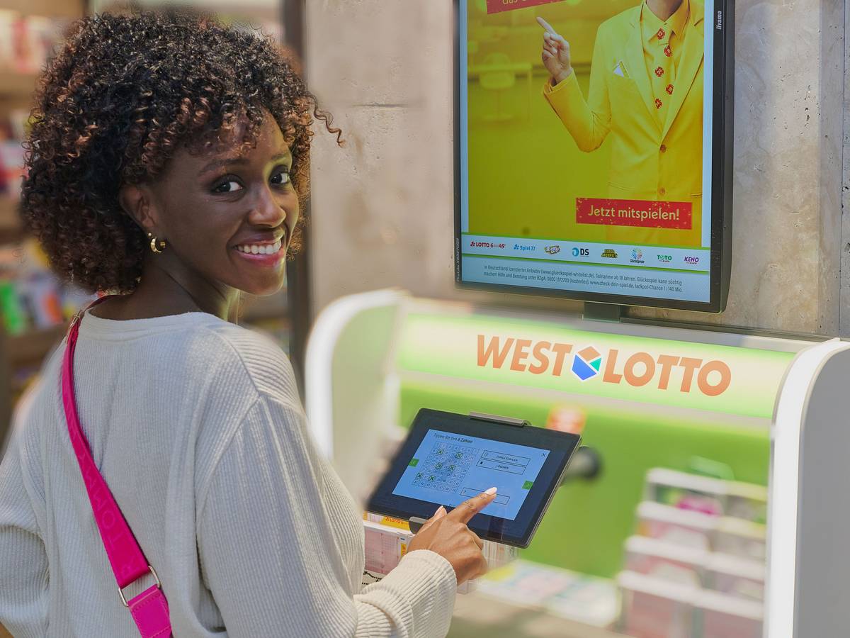 Eine Frau steht vor einem WestLotto-Schalter.
