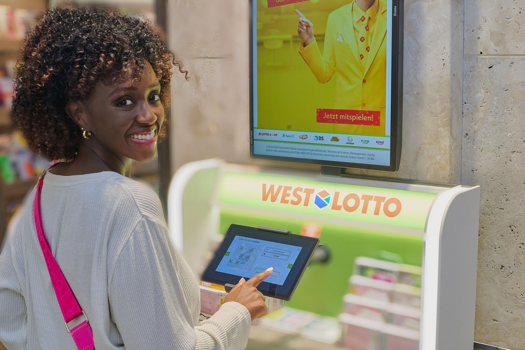 Eine Frau steht vor einem WestLotto-Schalter.