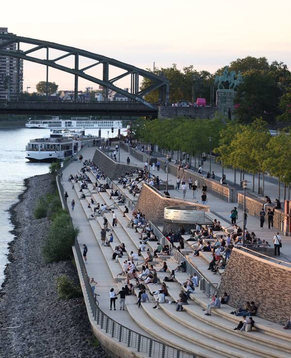Menschen genießen bei sommerlichen Temperaturen den Blick auf Rhein und Dom am Rheinboulevard. Die Temperaturen des Flusses sind angestiegen.