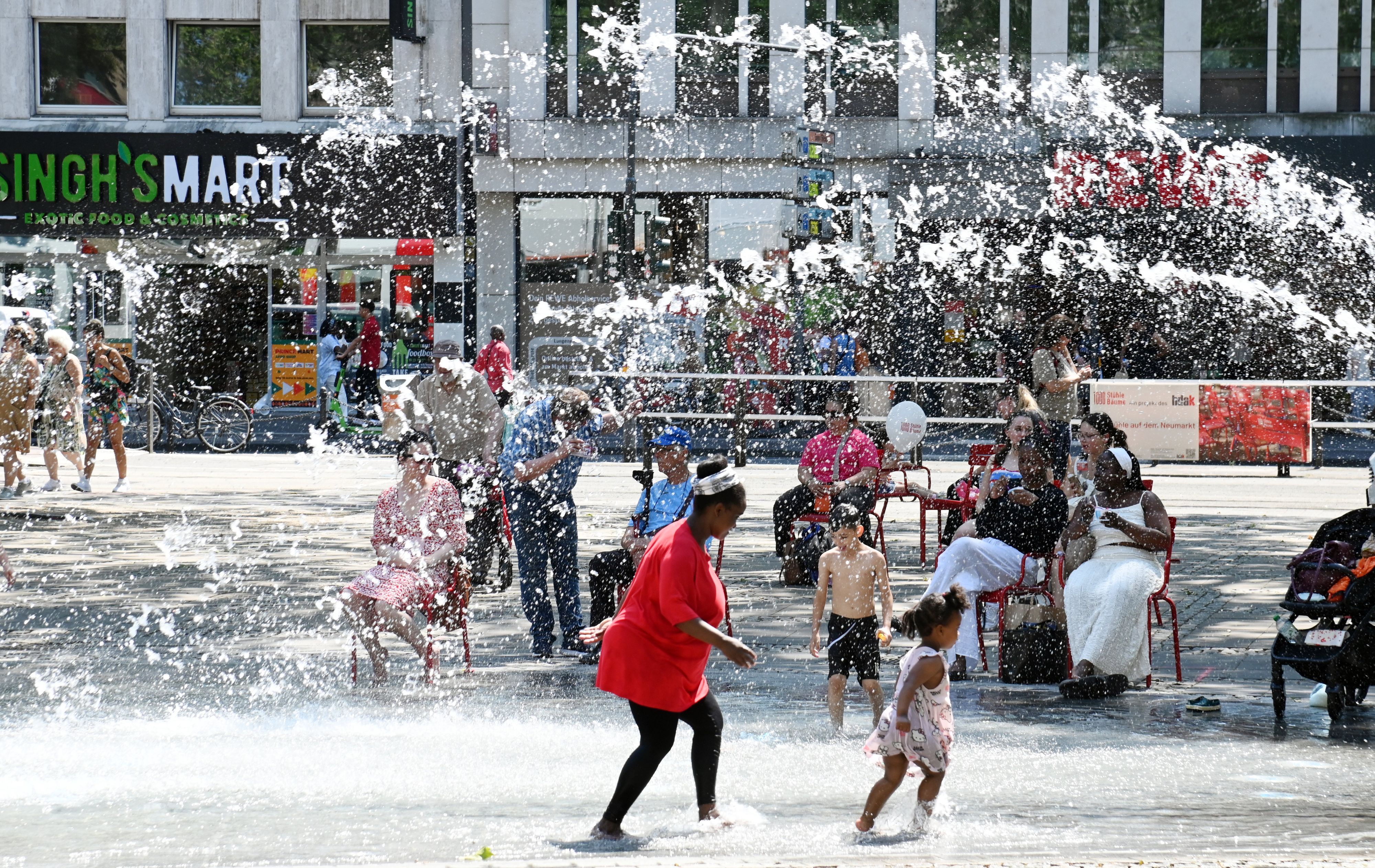 Hitzewelle in Köln: Am Neumarkt suchen die Menschen Abkühlung am Brunnen.