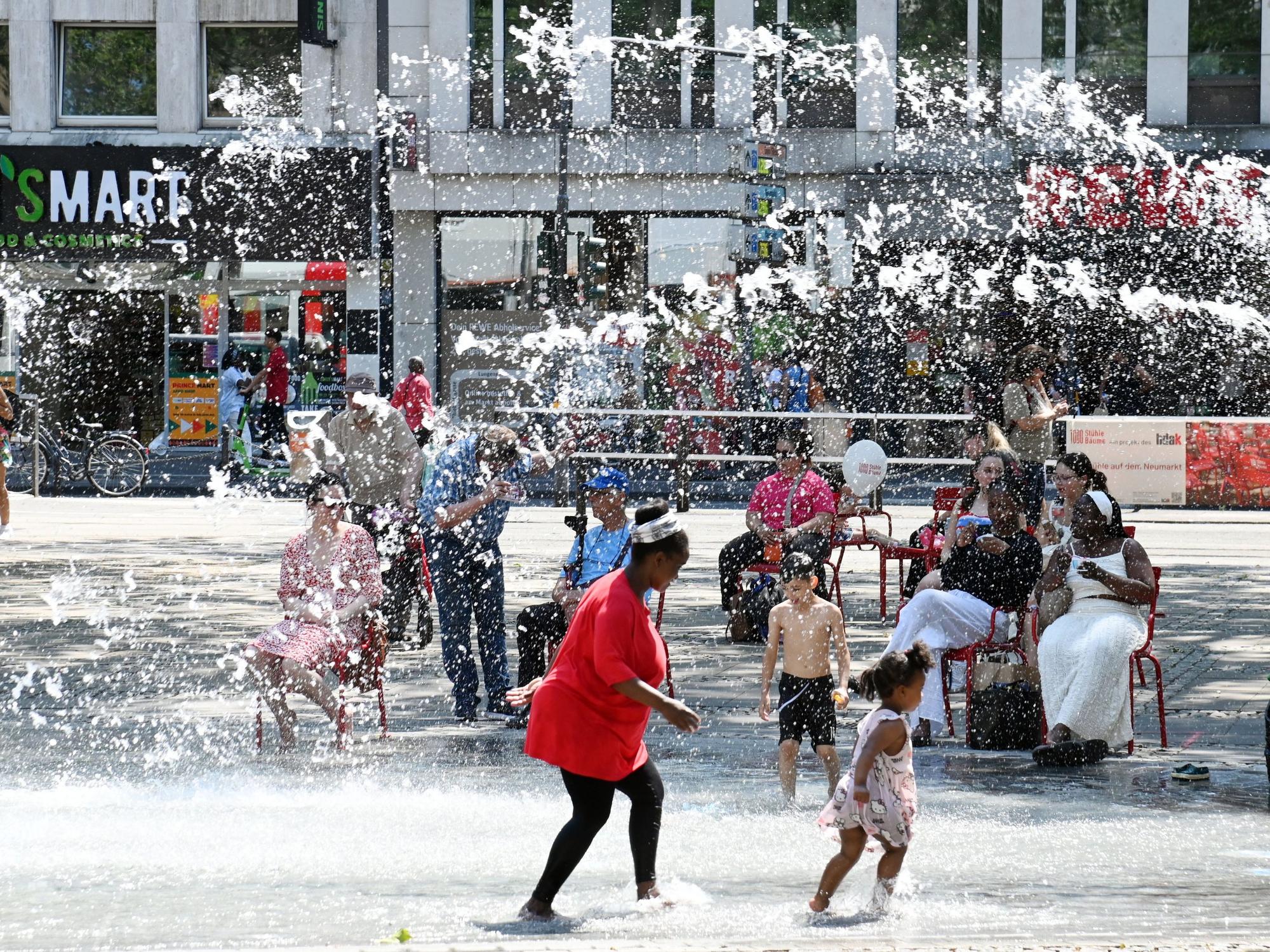 Hitzewelle in Köln: Am Neumarkt suchen die Menschen Abkühlung am Brunnen.