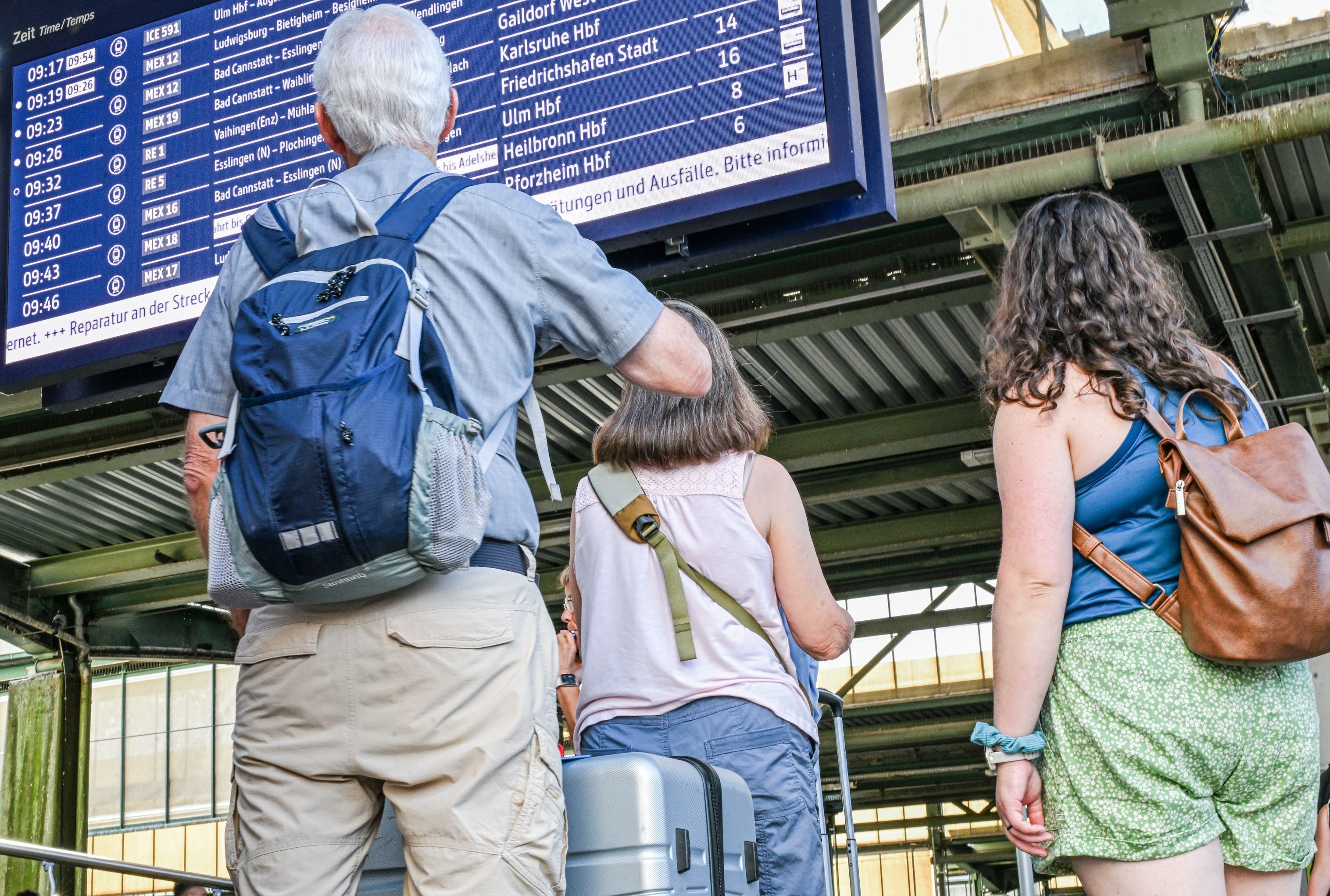 Reisende stehen auf dem Stuttgarter Hauptbahnhof vor einer Anzeigetafel.