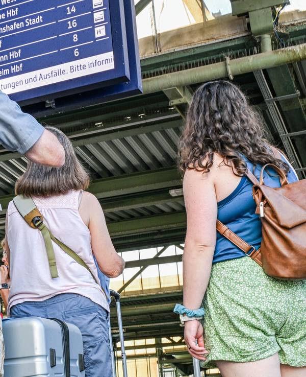 Reisende stehen auf dem Stuttgarter Hauptbahnhof vor einer Anzeigetafel.